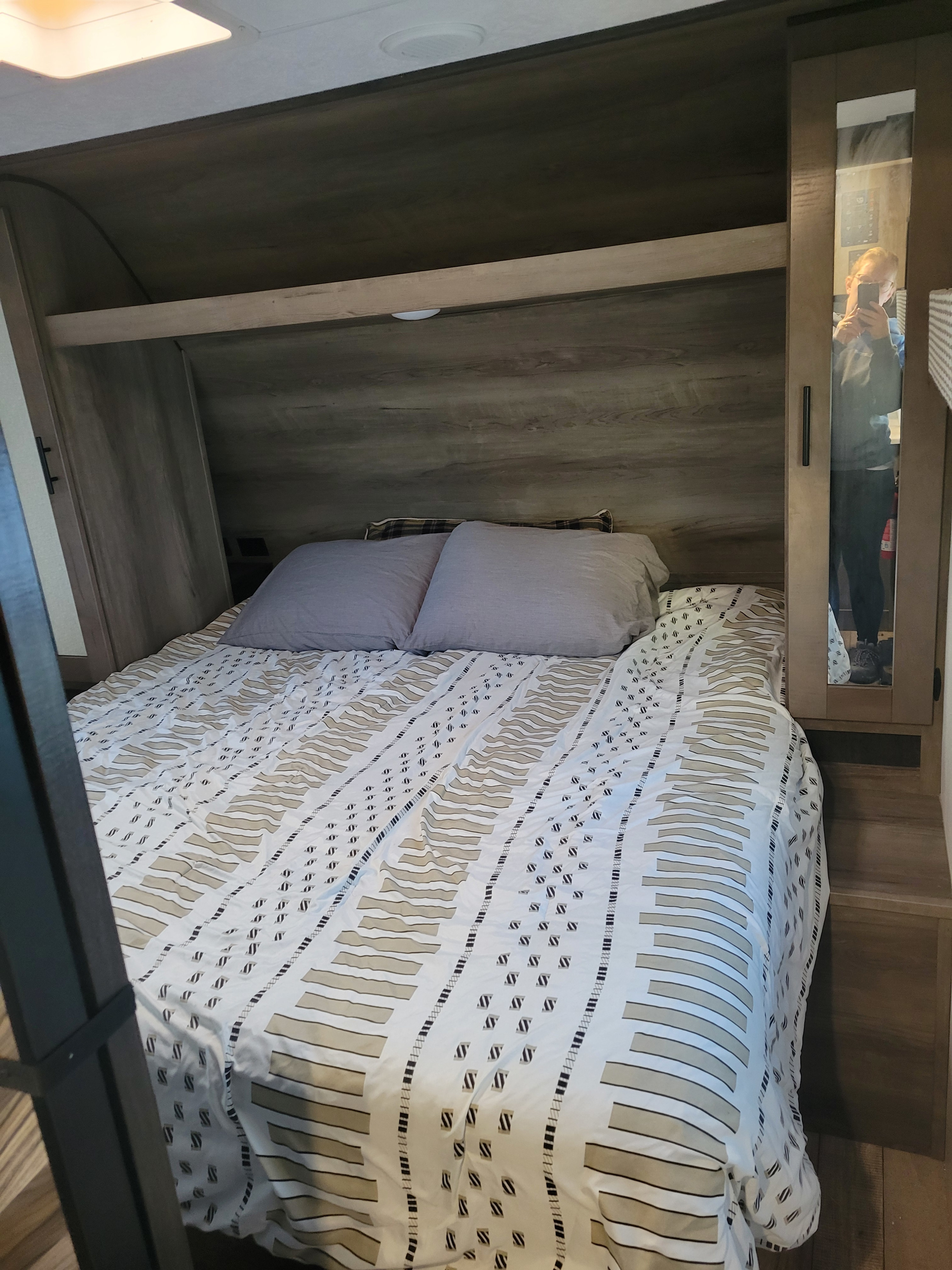 RV rental bedroom featuring a patterned bedspread, cozy pillows, and built-in storage with a mirrored closet.. KZ Confluence 2022