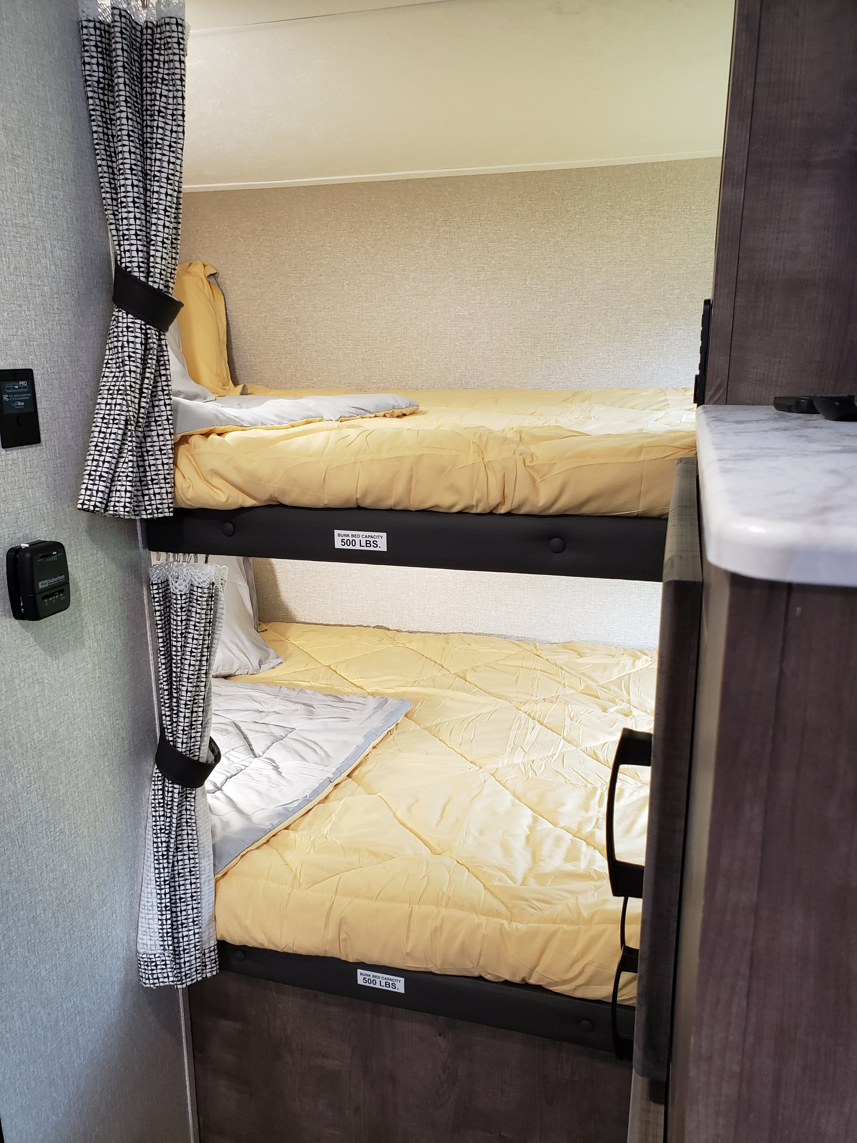 Inside an rv rental, this compact bedroom features comfortable bunk beds with yellow comforters, each rated for 500 lbs.. Venture Sonic SN211VDB 2022