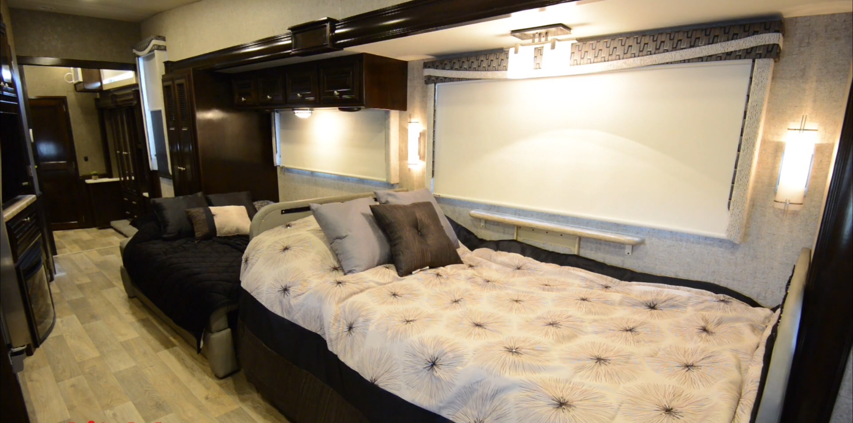 This spacious RV rental bedroom offers two beds, stylish bedding, dark wood cabinetry, and bright lighting for a comfortable travel experience.. Thor Outlaw 2017