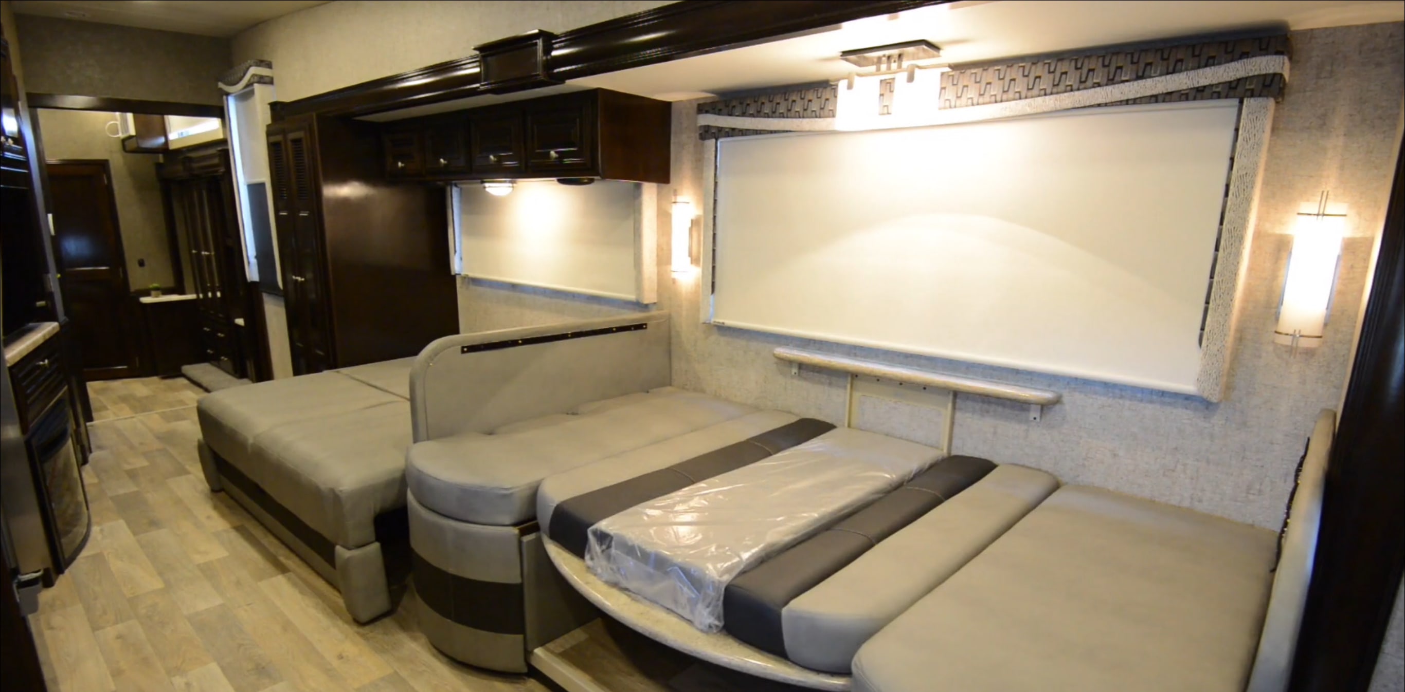 Explore this RV rental's versatile interior: a bright living area with plush, convertible seating, overhead cabinets, and sleek wall lighting.. Thor Outlaw 2017