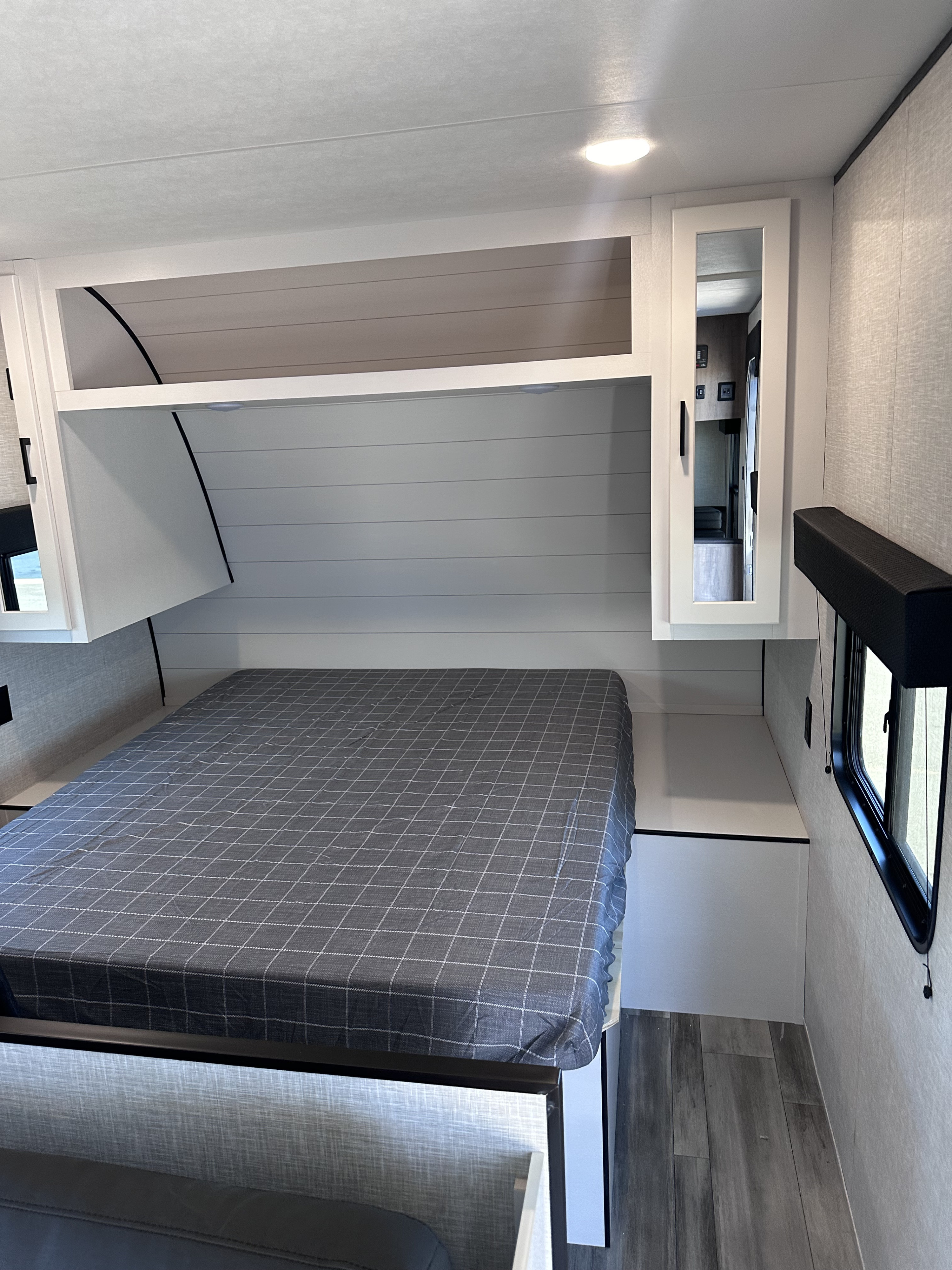 RV rental bedroom with gray bed, shiplap wall, overhead storage, and mirror cabinet. Features include a window.. Jayco Jayflight SLX 260BH 2024