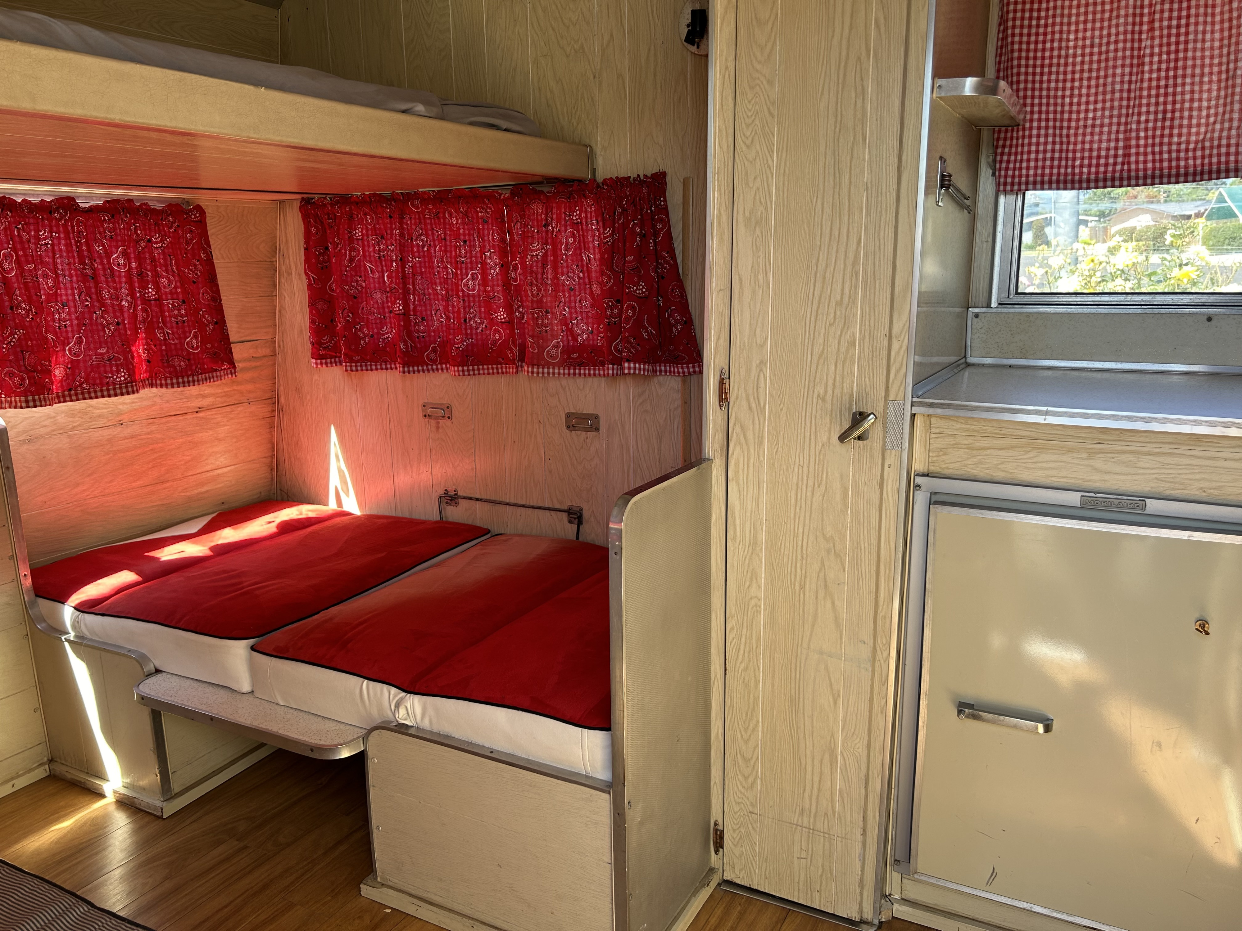Experience glamping in this vintage RV rental! Features cozy red beds, bunk, and a compact kitchen area with retro charm.. Aristocrat Lil Loafer 1965