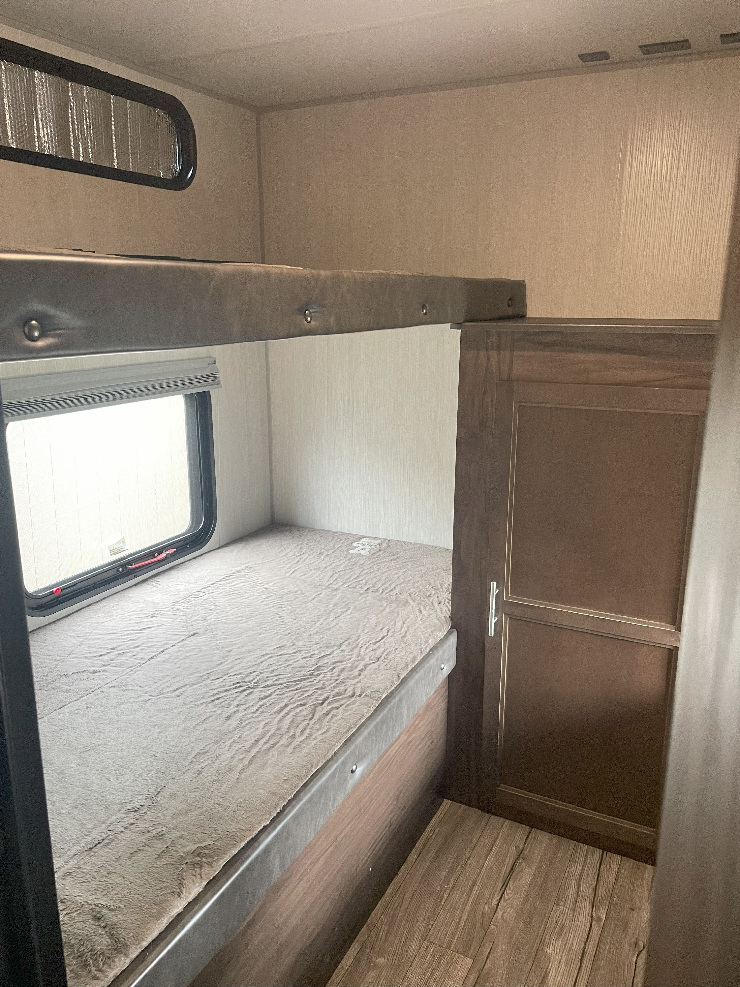 RV rental interior: cozy bunk beds with lower bed, window, and cabinet. Upper bunk above. Perfect for family adventures.. Forest River Cherokee Grey Wolf 2019