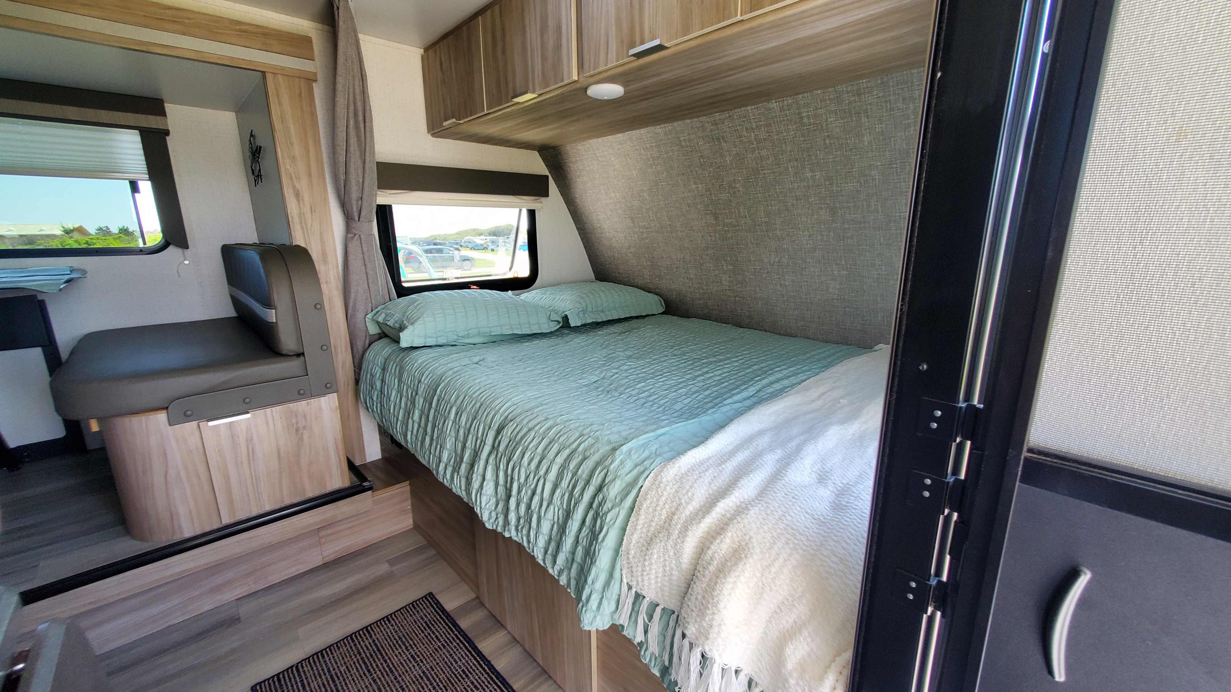 Cozy RV rental interior with a comfortable bed, dinette, and bright windows offering a view of the outdoors.. Winnebago Minnie Winnie 2021