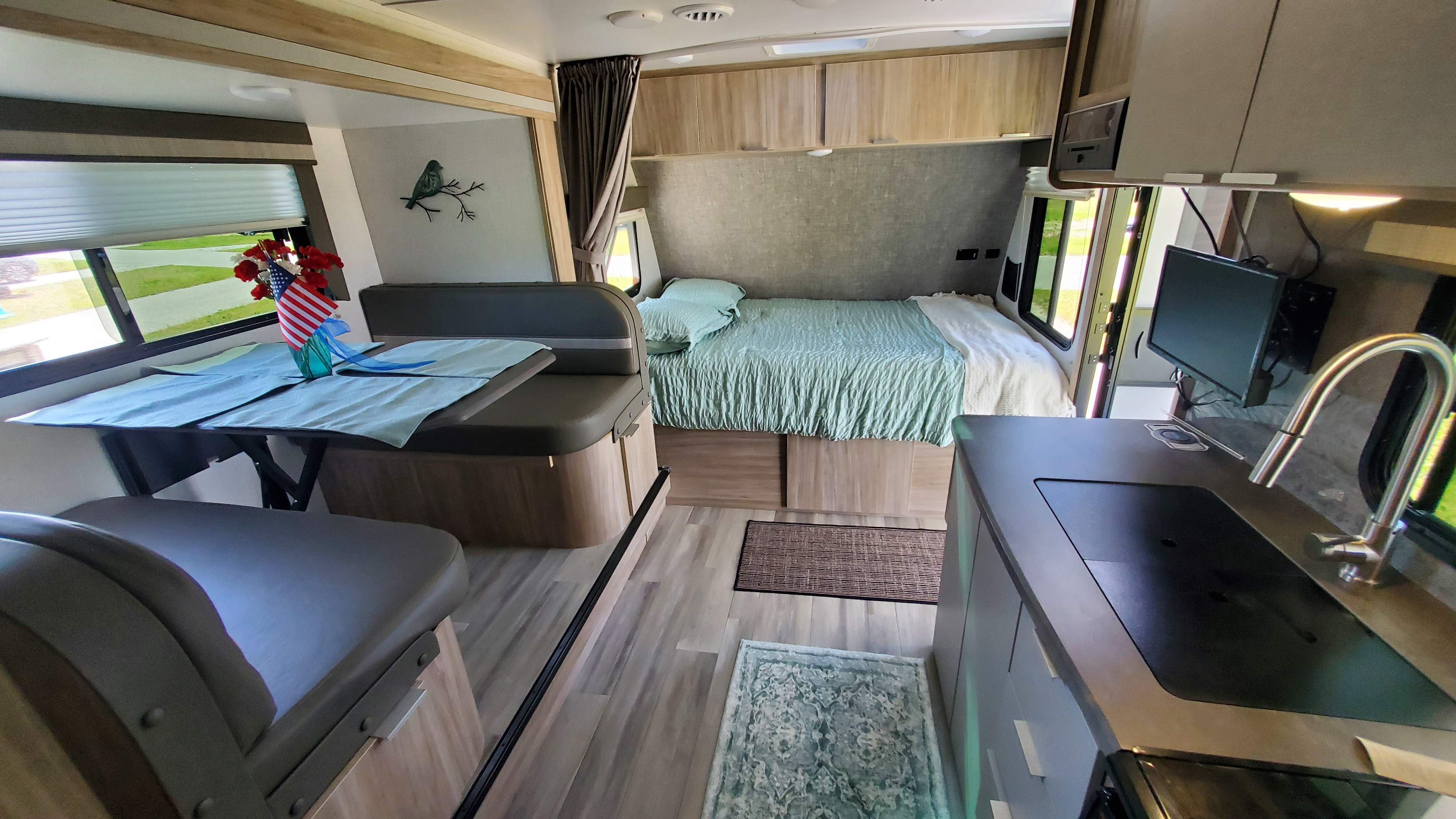 Spacious rv rental interior featuring a cozy bedroom, dinette, and kitchenette. Perfect for travel adventures!. Winnebago Minnie Winnie 2021