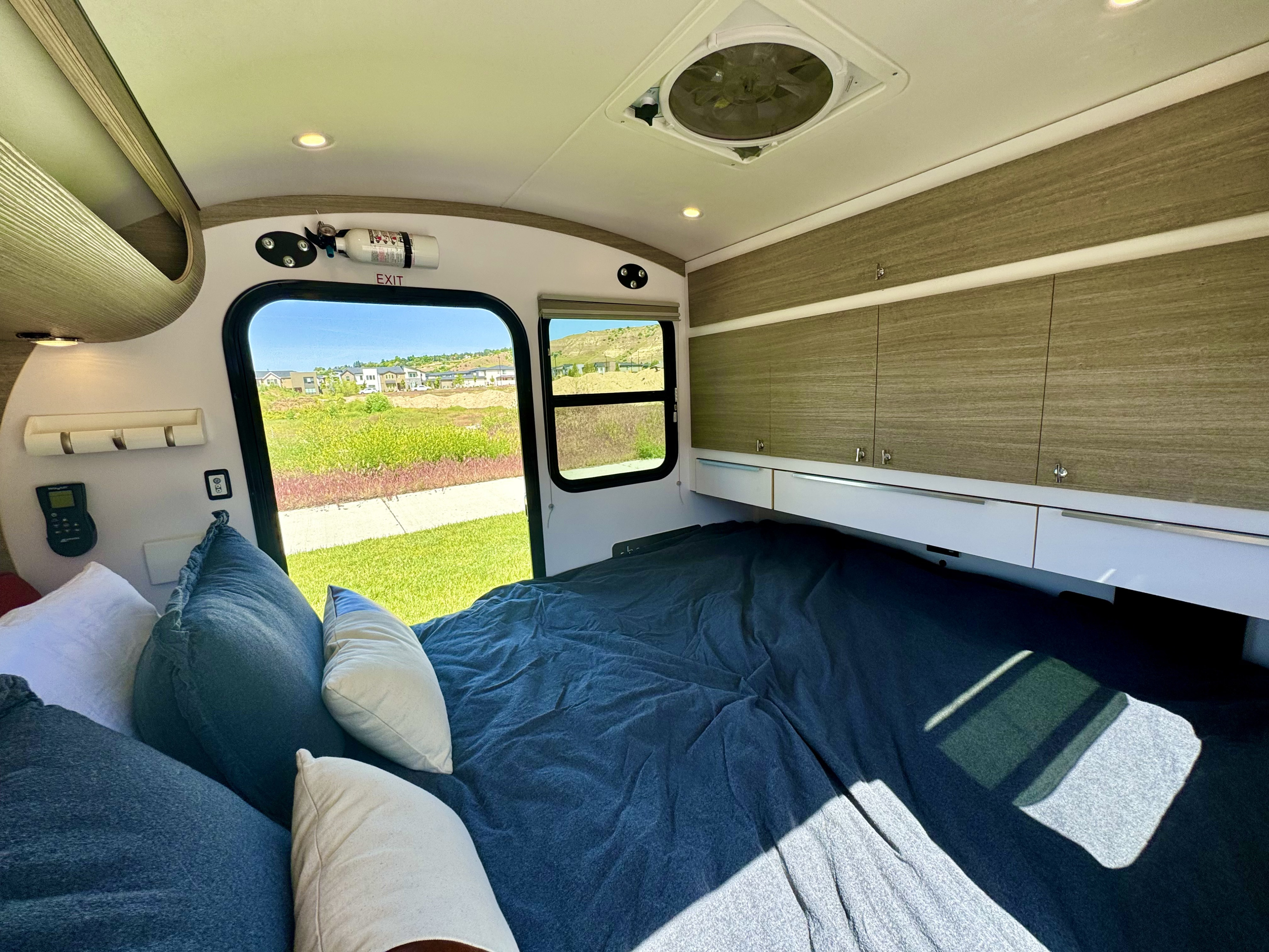 Cozy rv rental interior with a comfy bed, large windows showcasing outdoor views, and ample storage.. Bean Trailer Bean Trailer Trailer 2019