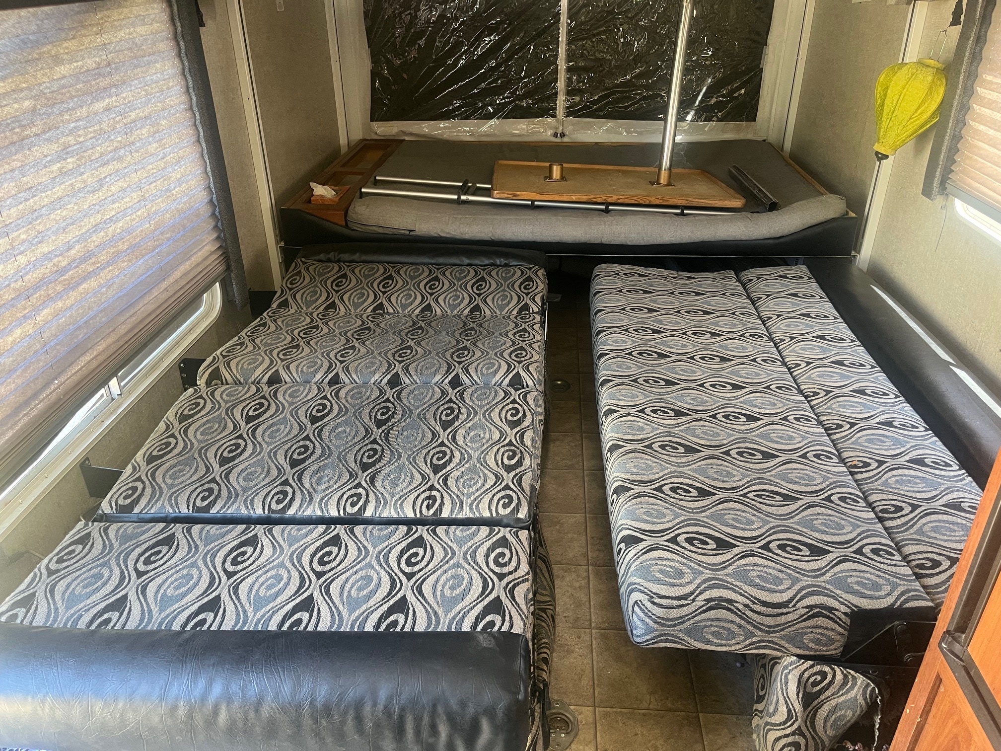 RV rental interior: Two patterned, convertible sofa beds face a dining area with a table. Rear has a clear tent-like pop-out bunk.. Eclipse Recreational Vehicles Stellar 2011