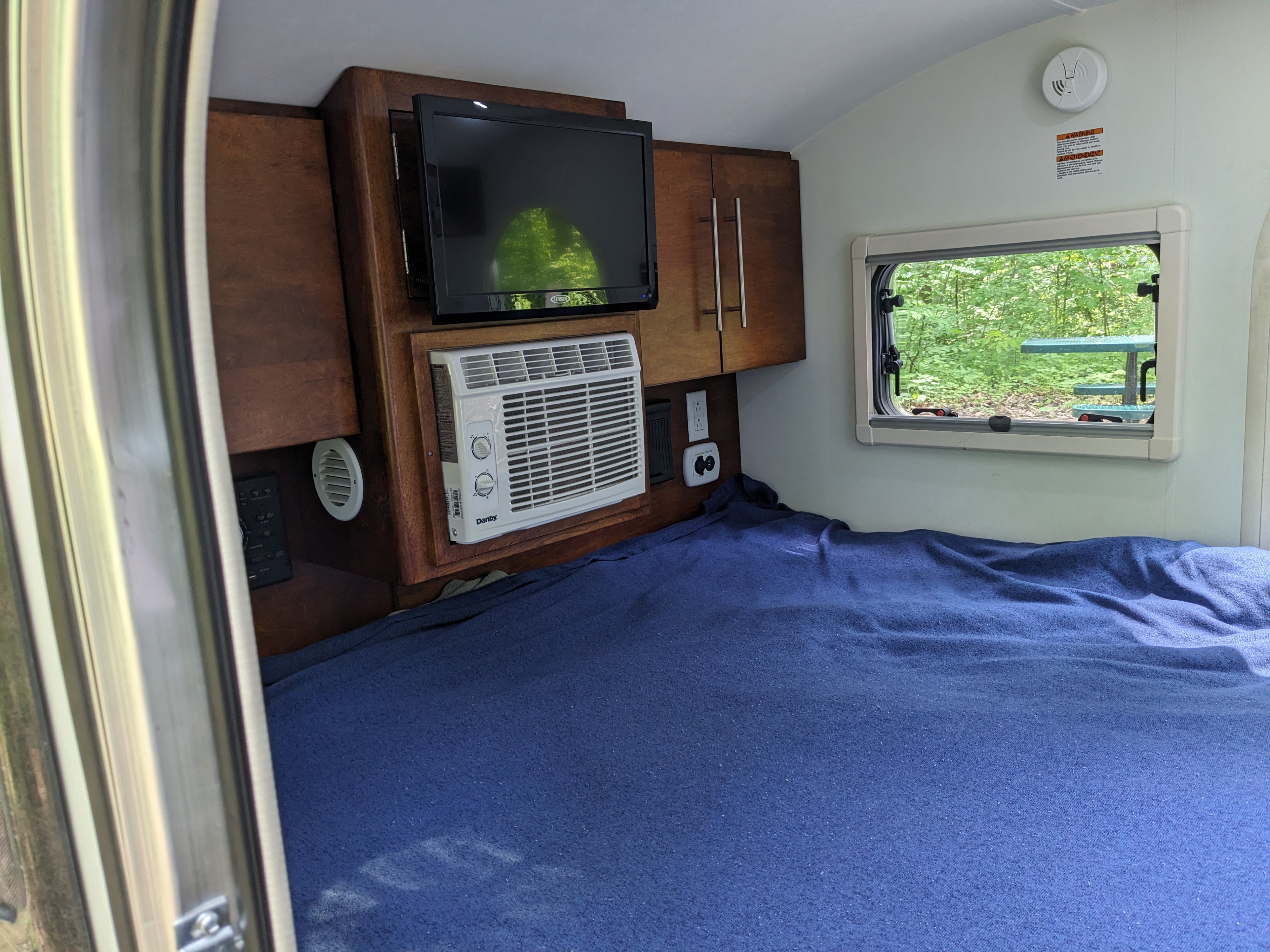 RV rental interior featuring a comfy bed, TV, AC, and a scenic window view. Perfect for compact adventures.. nuCamp T@G 2018