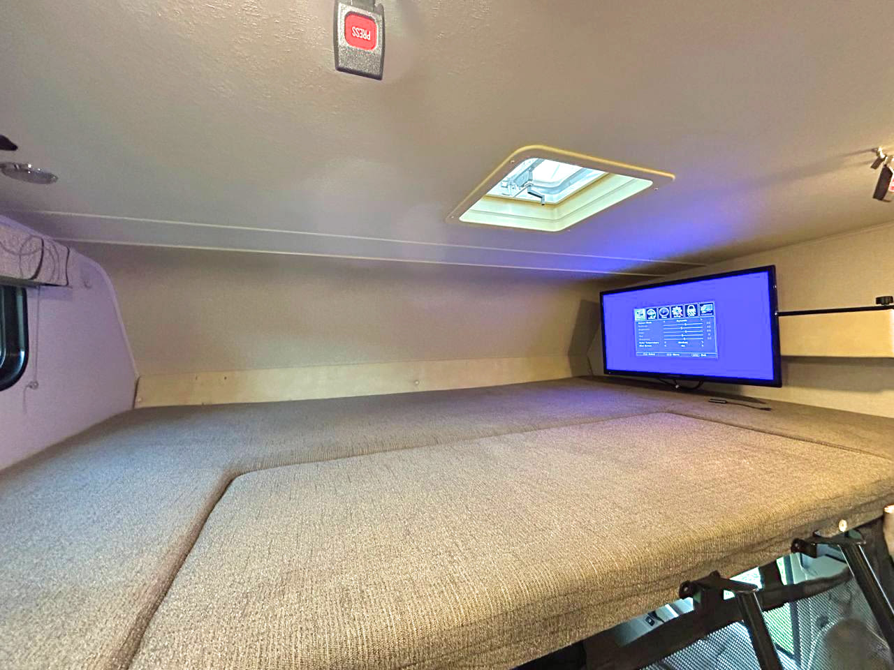 This RV rental features a cozy, fabric-covered over-cab bunk bed with a wall-mounted TV and ceiling skylight.. COACHMEN LEPRECHAUN 2017