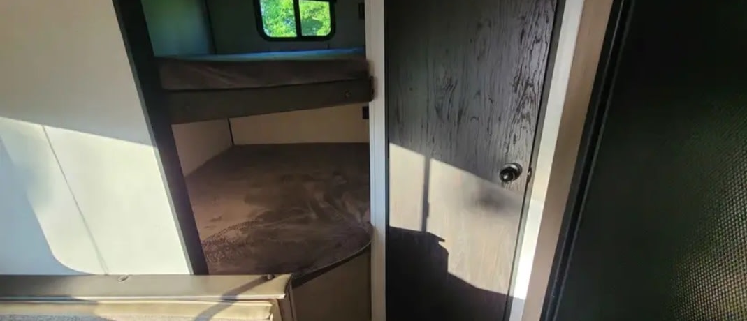 Step inside this RV rental! Features comfy bunk beds, a nature view window, and a sleek dark door. Perfect for camping adventures.. Keystone RV Hideout LHS 2020