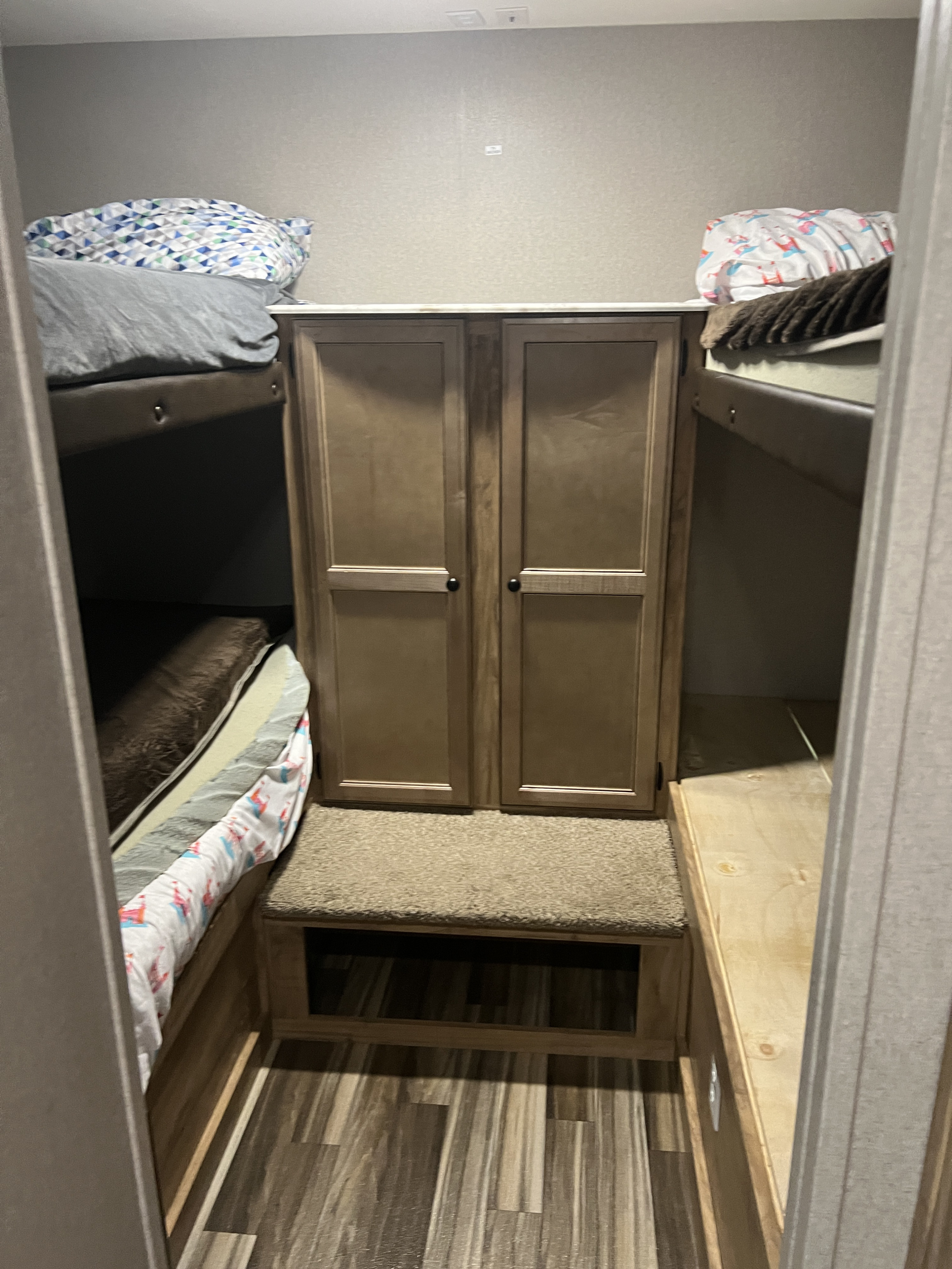 Cozy RV rental bunk beds with a central storage cabinet and carpeted step, perfect for family adventures.. Coachmen 29SE Bunkhouse 2019
