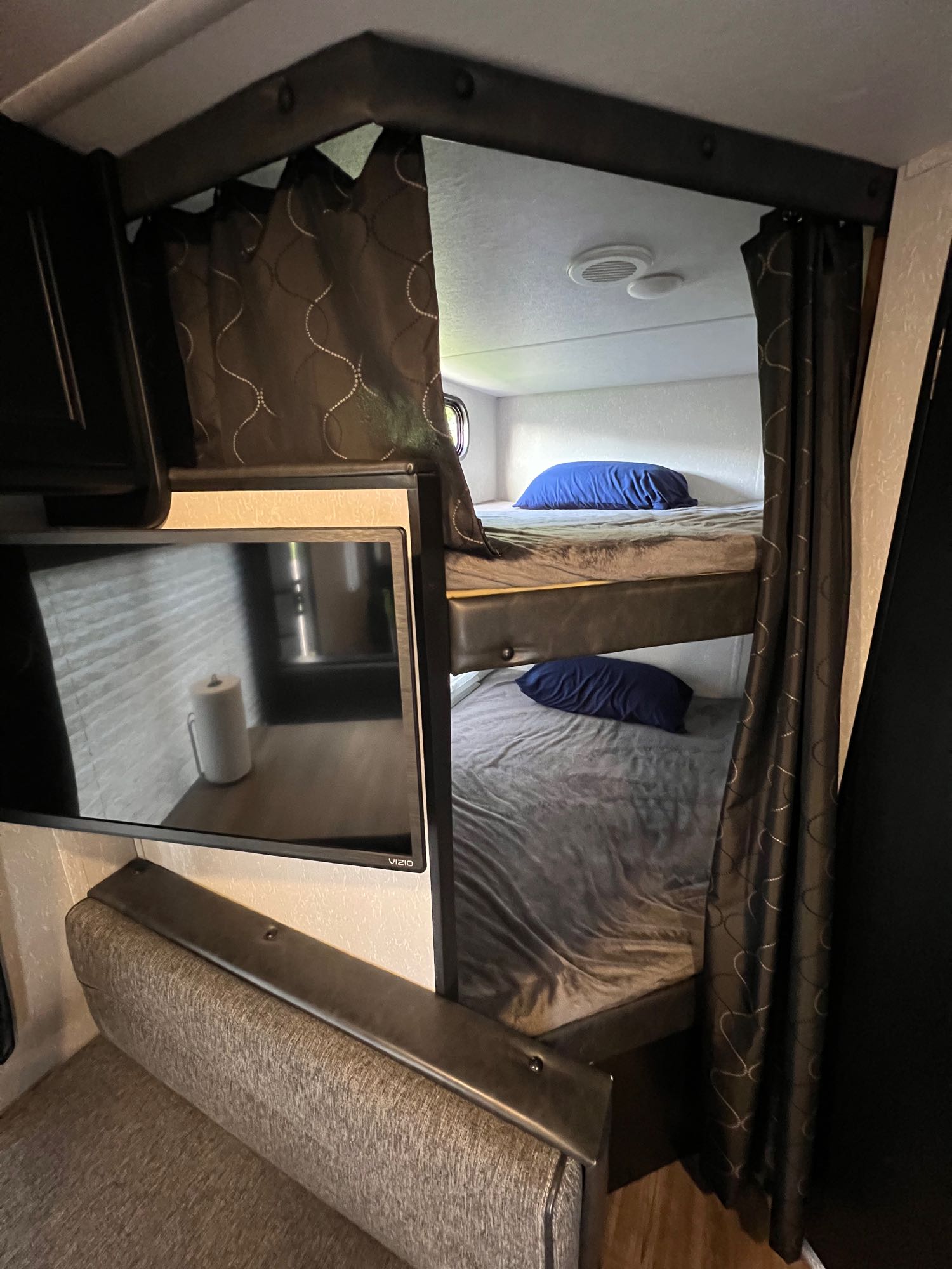 Compact rv rental interior with cozy bunk beds, a mounted TV reflecting the space, and integrated seating.. Forest River Cherokee Grey Wolf Limited 2021