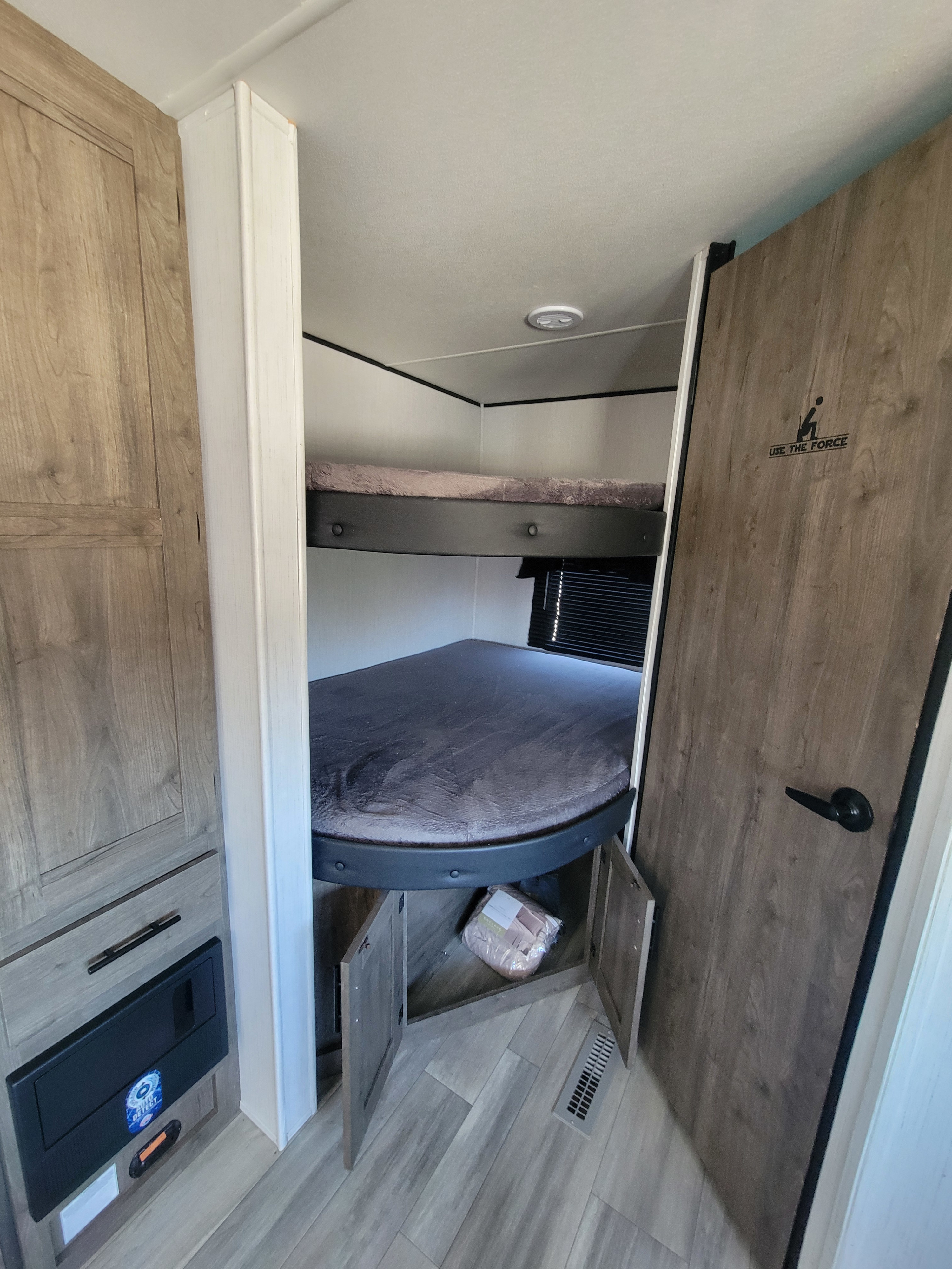 Interior of an RV rental showing cozy bunk beds, lower storage, and a unique bathroom door. Ideal for family trips.. Heartland RVs Pioneer 2022