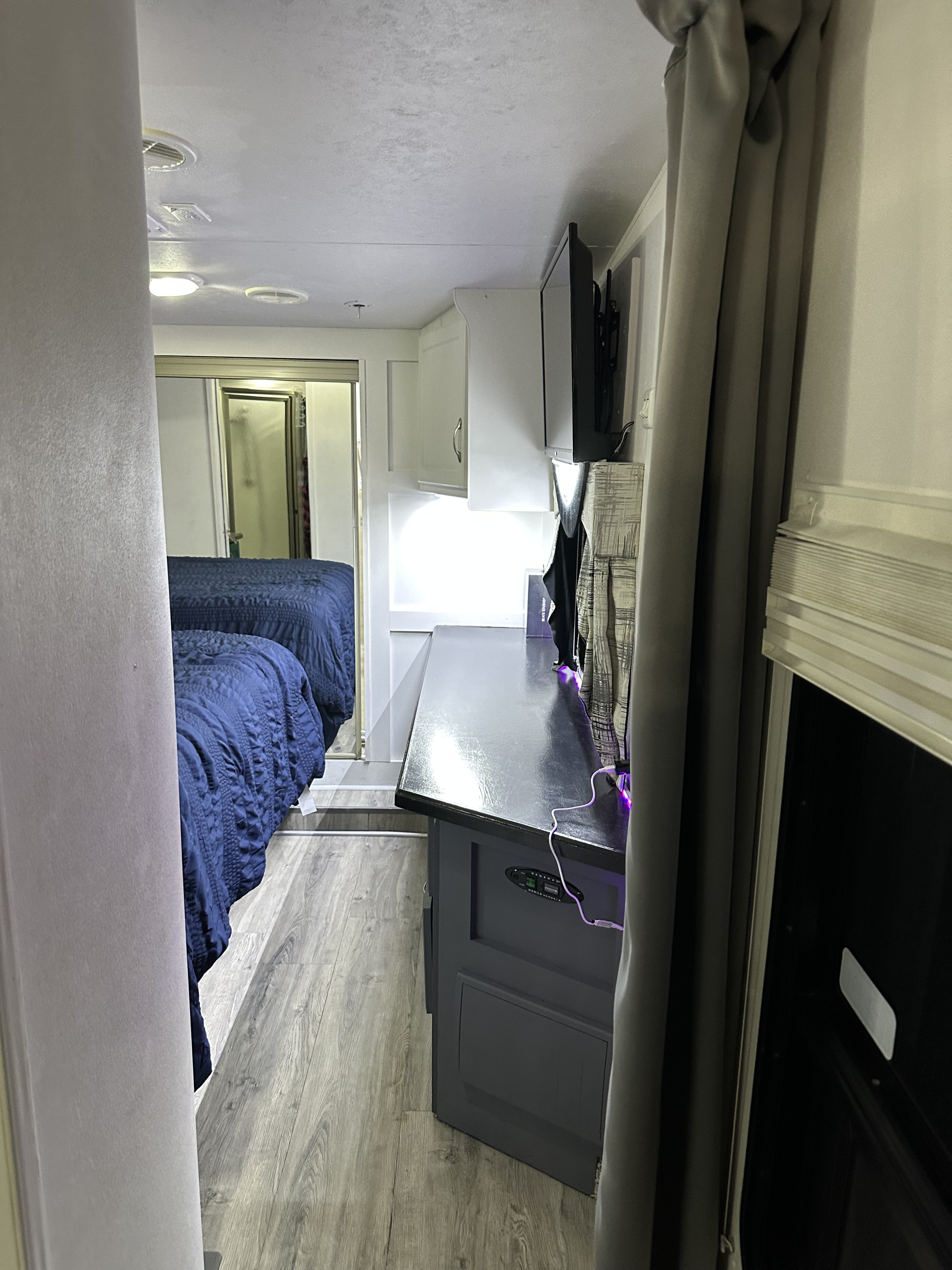 Inside an RV rental, this spacious interior features a bedroom with two blue beds, a shower, and a living area with a TV.. Sportsman M-40P 2008