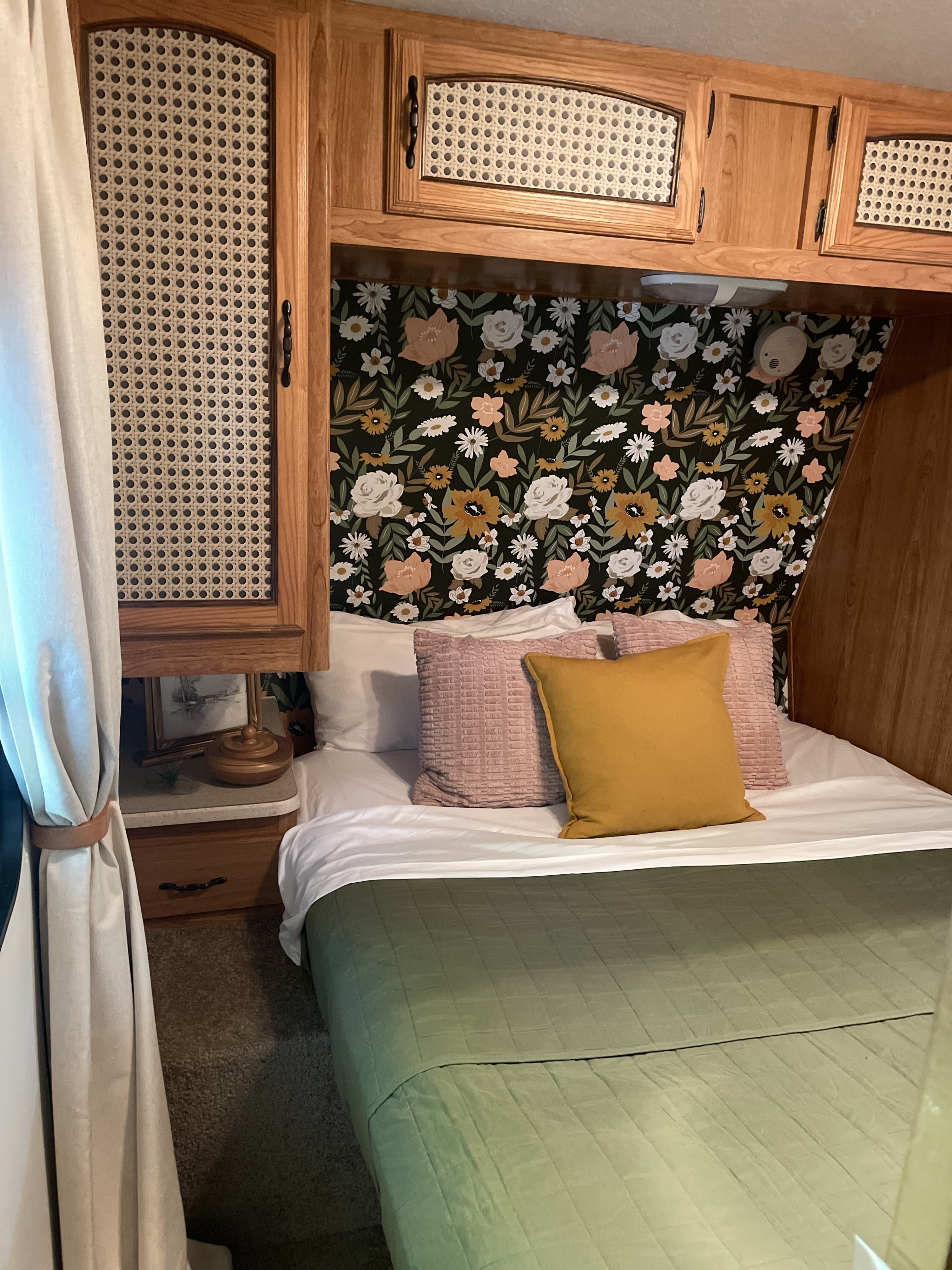 Updated RV rental bedroom: dark floral wallpaper, cane cabinet inserts, green quilted bedding, and cozy decor.. Forest River Palomino Puma 2010