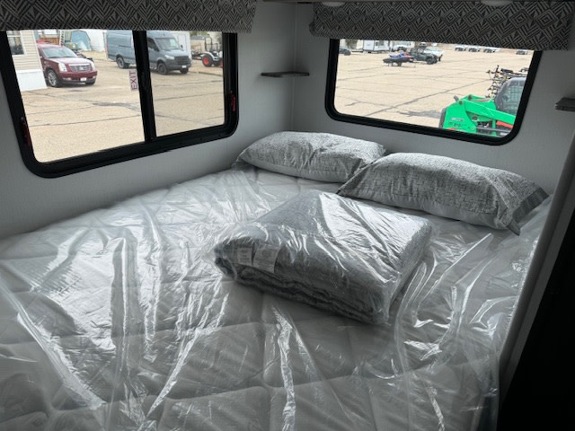 RV rental bedroom featuring a clean bed with new bedding in plastic, ready for comfortable travels.. Forest River 2351LE 2024