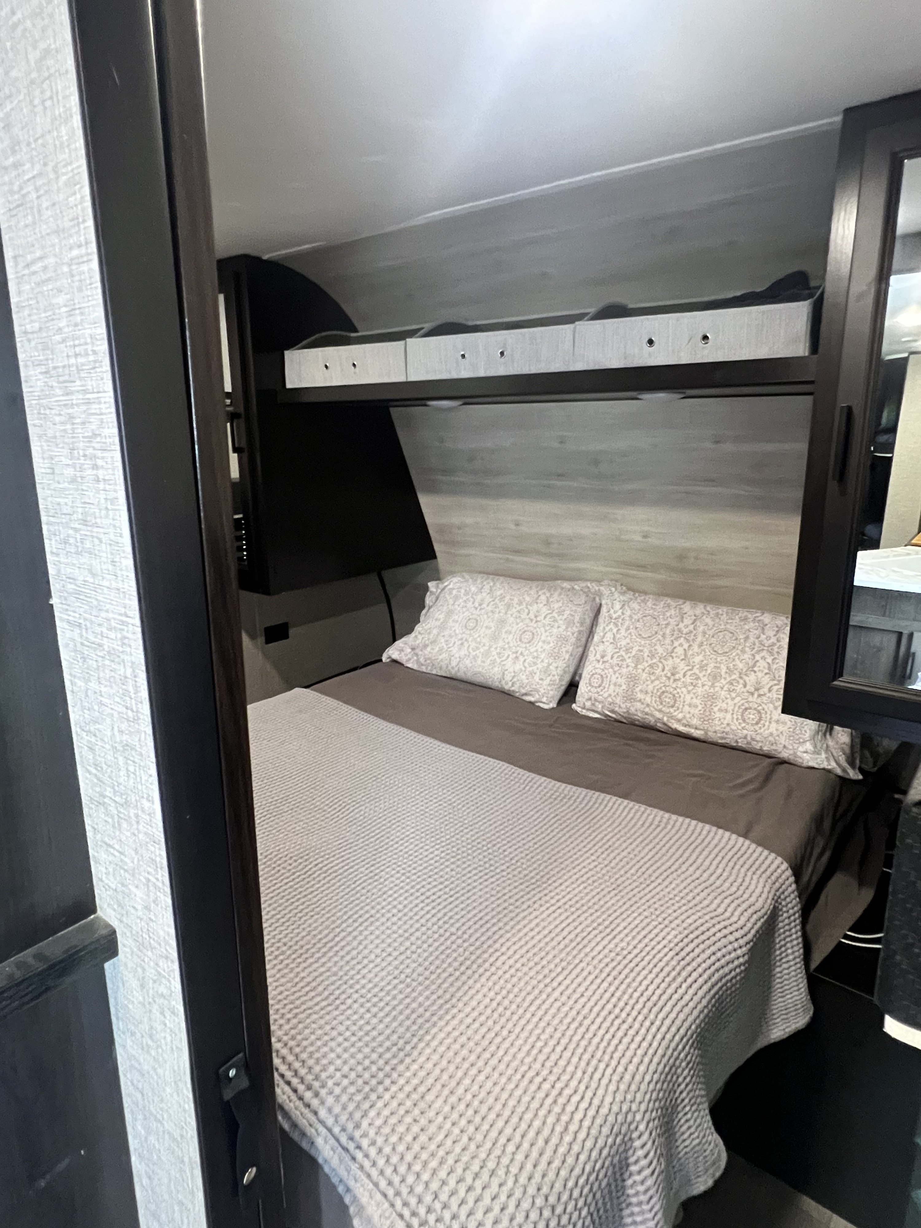 Cozy RV rental bedroom featuring a comfy bed with patterned pillows and convenient overhead storage.. Jayco Jay Flight SLX Rocky Mountain Edition 2022