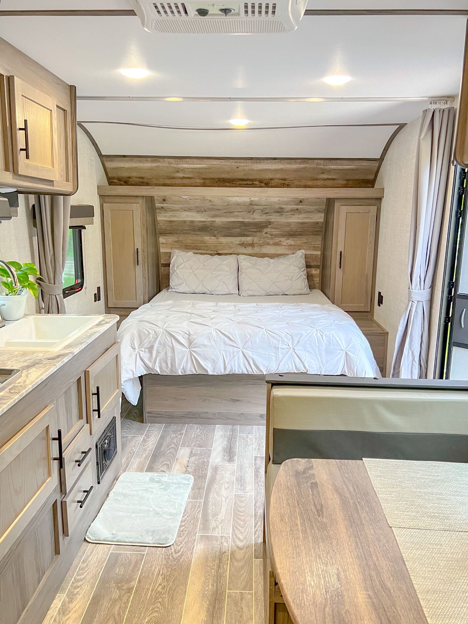 Cozy modern RV rental interior featuring a comfortable bed, kitchenette, and dinette area, ideal for travel adventures.. Gulf Stream Ameri-Lite 2022