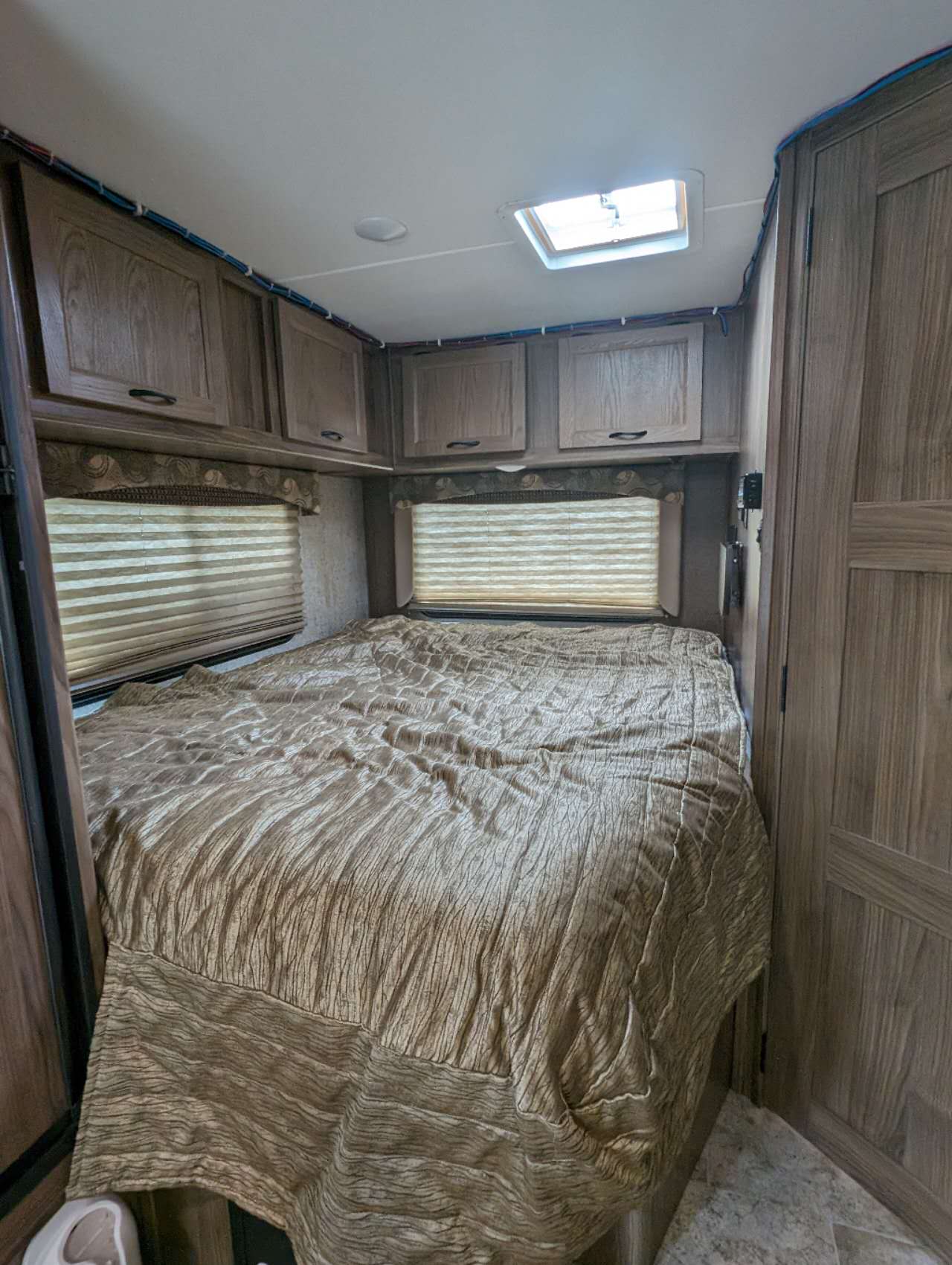 Spacious RV rental bedroom featuring a comfy bed, overhead cabinets, blinds on windows, and a ceiling skylight.. Forest River Coachmen Freelander 2018