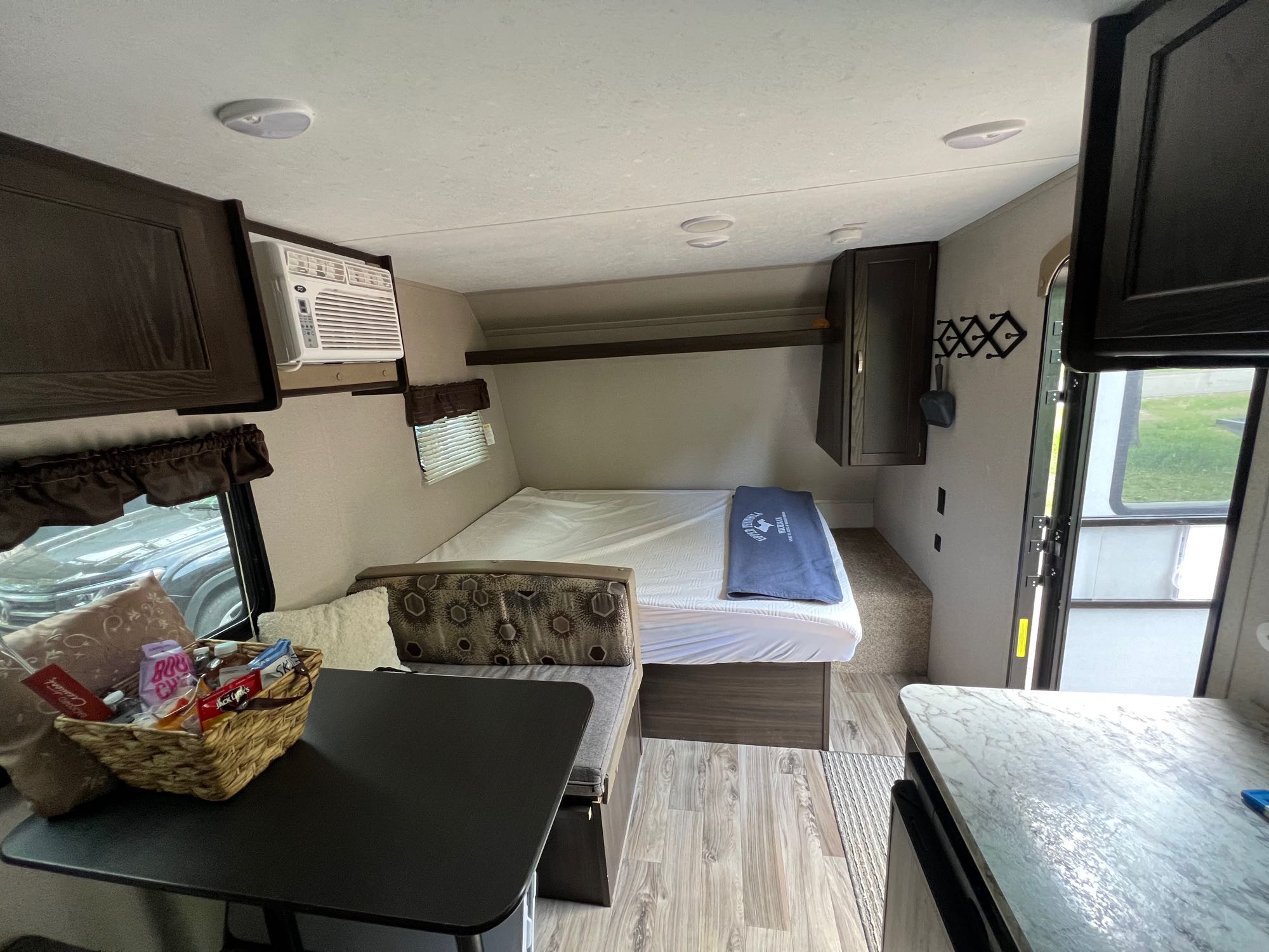 View inside an RV rental: a compact interior with bed, dining area, AC, and small kitchen counter.. Keystone RV Springdale 2018