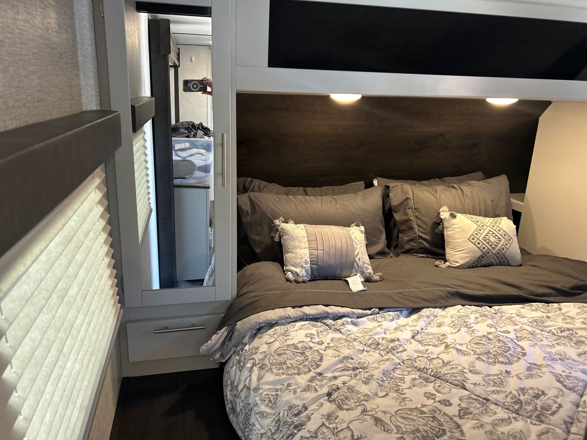 Comfortable RV rental bedroom with a patterned comforter, dark grey pillows, and overhead lighting. Ideal for your next camper adventure.. Keystone RV Bullet Ultra Lite 2021