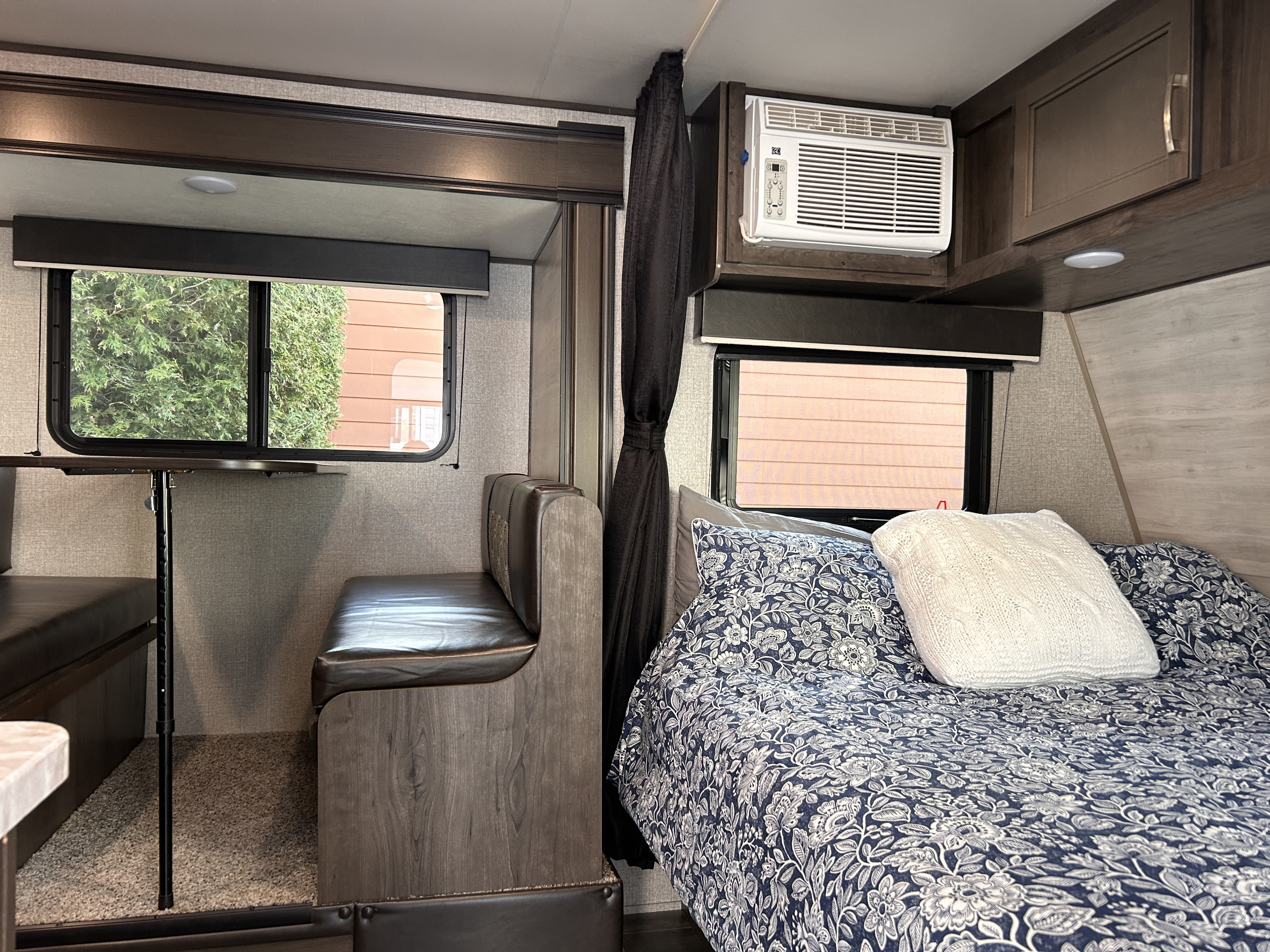 Inside an RV rental: a comfortable dinette and bed with floral covers, equipped with an AC unit for your travels.. Jayco Jay Flight SLX 2021