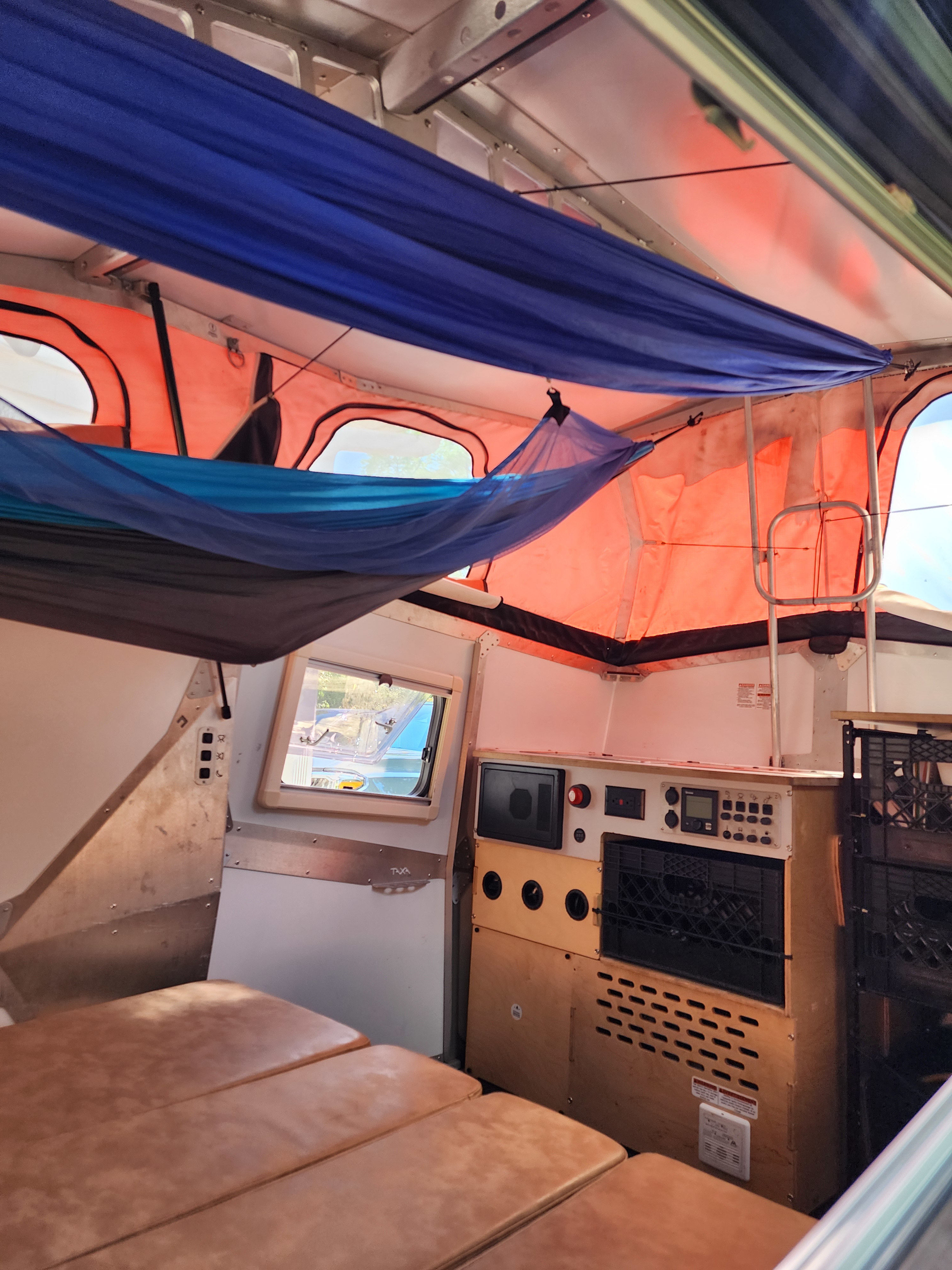 Experience comfort in this unique RV rental interior, featuring suspended hammocks, a convertible bed, and onboard controls.. TAXA TAXA Trailer 2021