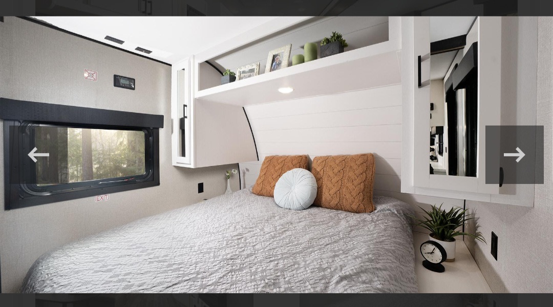 Cozy RV rental bedroom with a comfortable bed, window view, and integrated storage, perfect for your travels.. Highland Ridge RV Open Range 2024