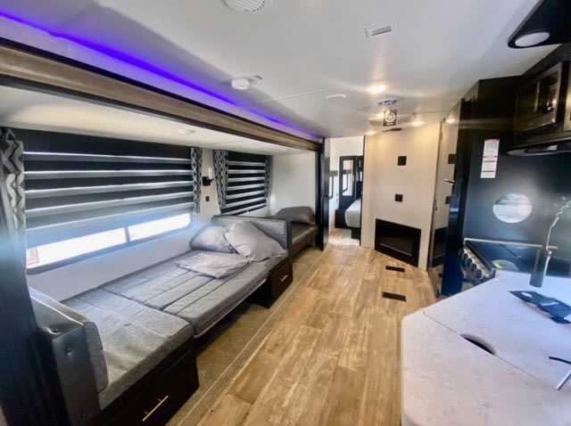 Explore this modern RV rental interior featuring a versatile living/sleeping area, full kitchen, and rear bedroom.. Forest River Cherokee Grey Wolf Black Label 2023