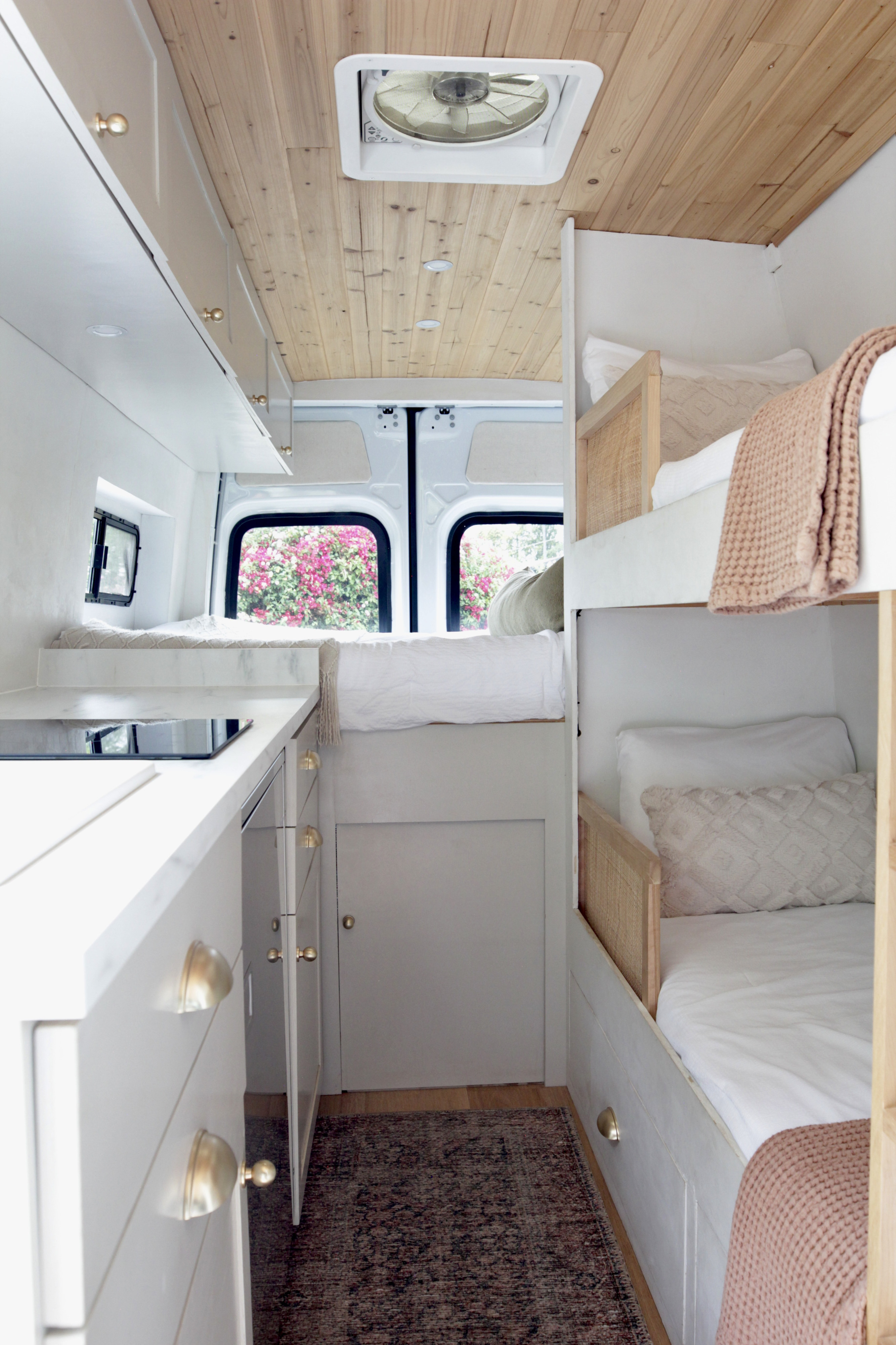 RV rental: Bright, modern camper interior with a cozy bunk bed area, sleek kitchenette, and wood-paneled ceiling.. Mercedes-Benz Sprinter 2021
