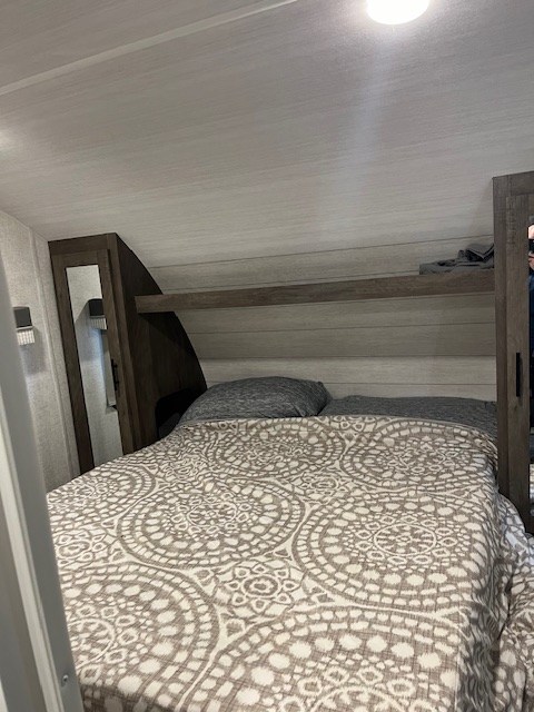 RV rental bedroom interior, featuring a cozy bed with patterned duvet, pillows, and functional built-in storage.. Forest River Salem Cruise Lite 2021