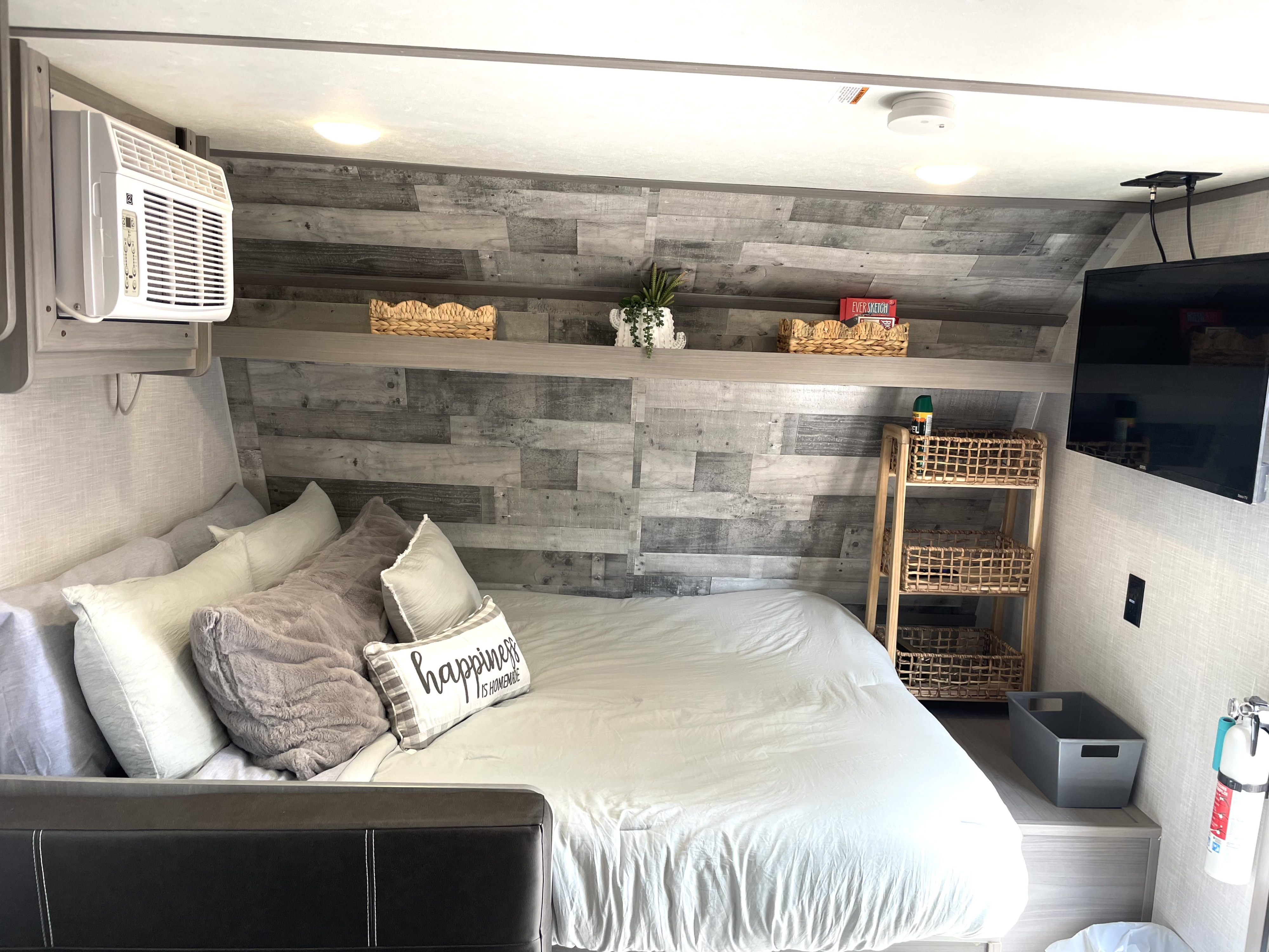 Cozy RV rental bedroom featuring a comfortable bed, wall-mounted AC, TV, and decorative storage for compact living.. Dutchmen Coleman Lantern LT 2023
