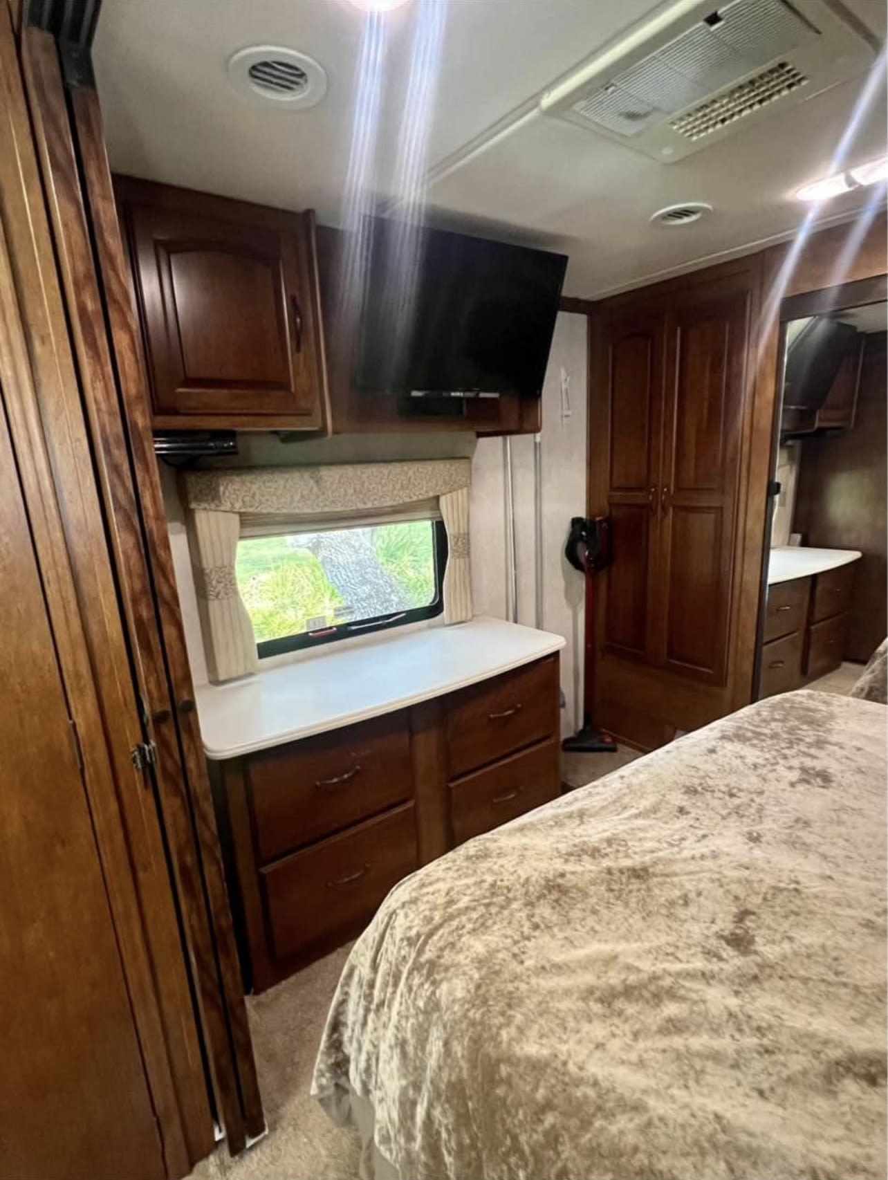 This RV rental bedroom features a plush bed, wall-mounted TV, window, and rich wood cabinets/drawers for storage.. coachmen coachmen cross-country 390 2013