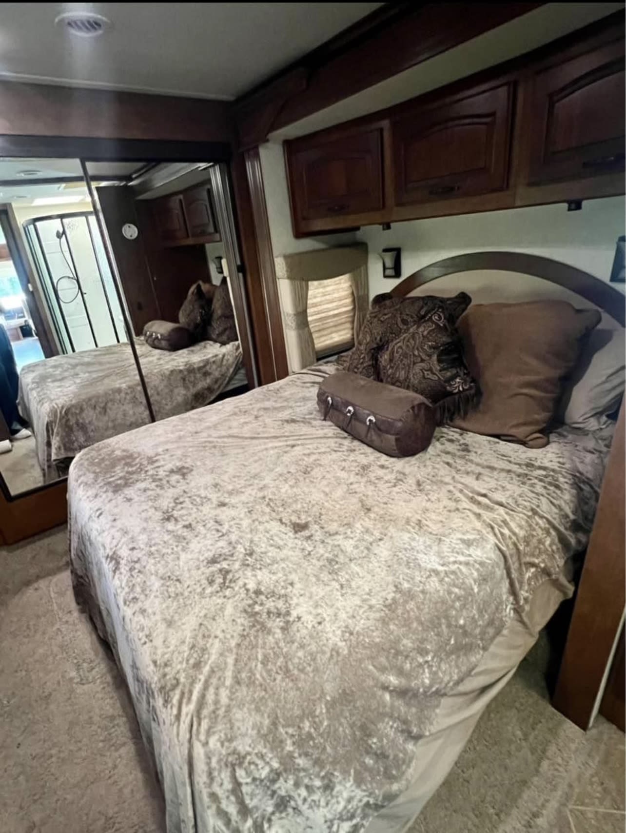 Cozy RV rental bedroom with plush bed, overhead cabinets, and mirrored closet reflecting a shower.. coachmen coachmen cross-country 390 2013