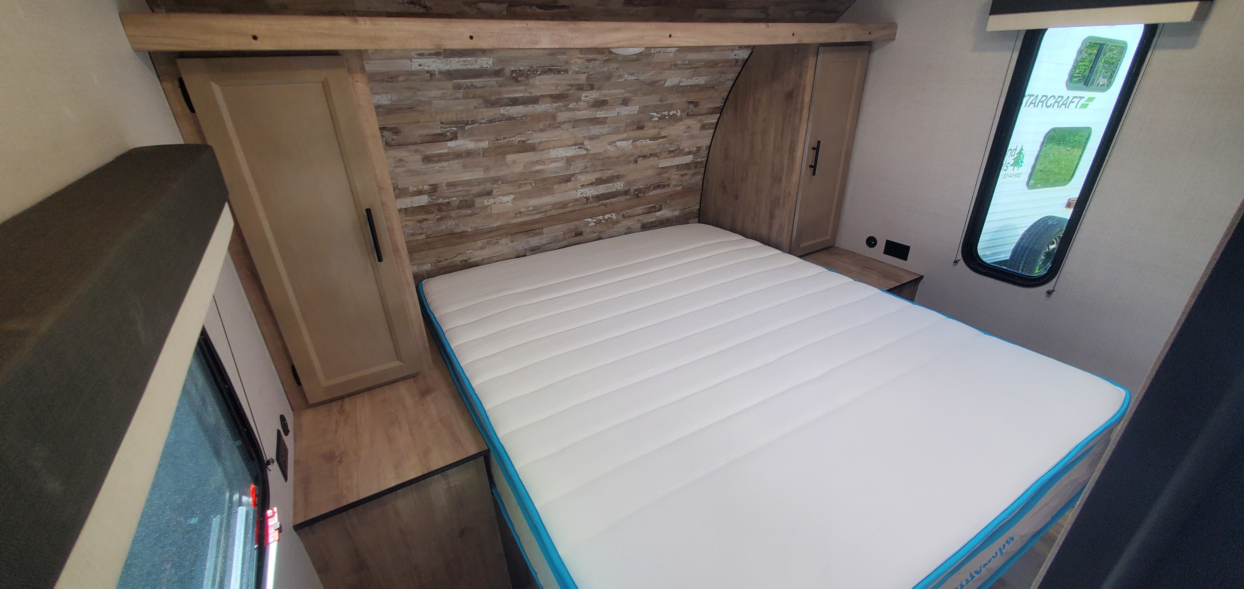 Bright RV rental bedroom showcasing a plush white mattress, wood-look headboard, and built-in storage.. Gulf Stream Trailmaster 2023