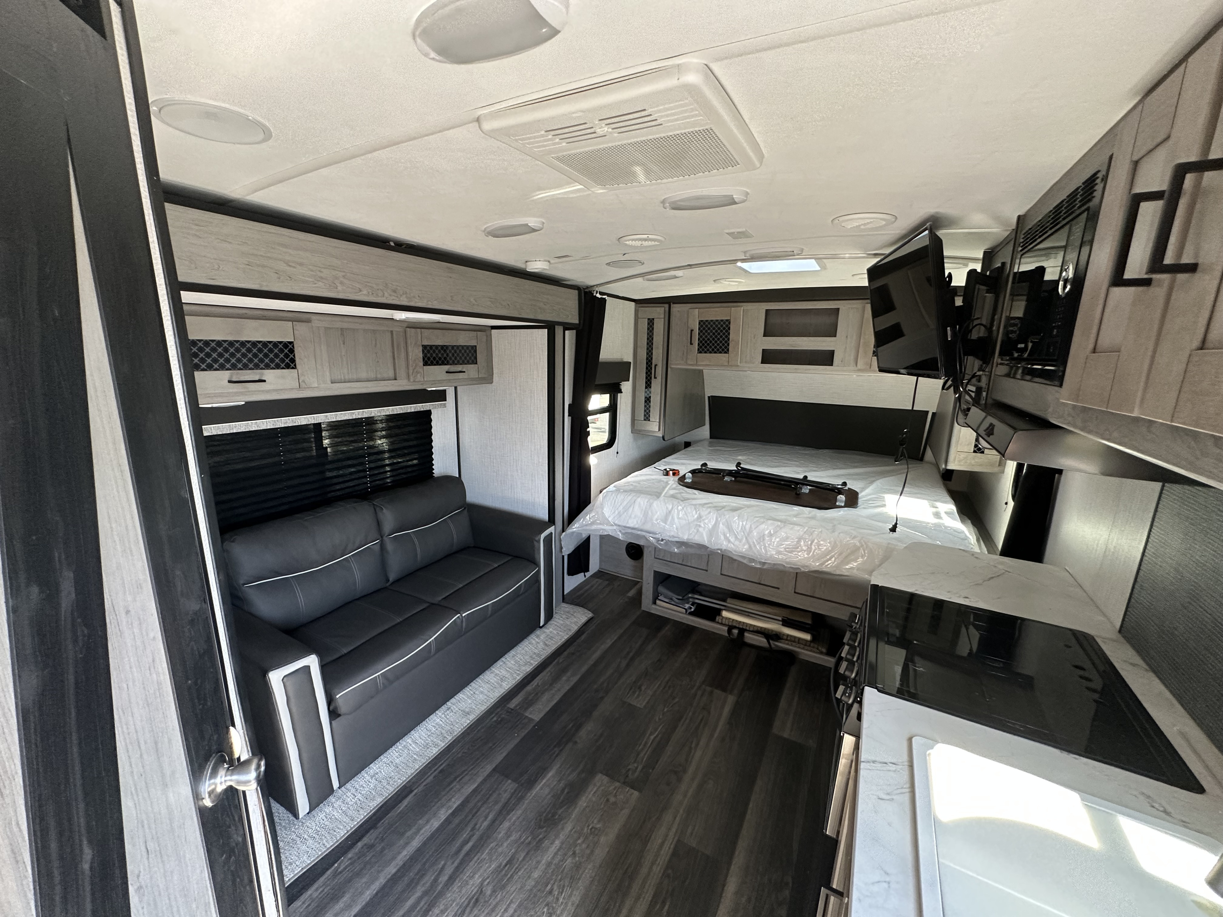 Modern RV rental interior with a comfortable bed, sofa, and functional kitchen area. Ideal for travel.. Heartland RVs Mallard 2021