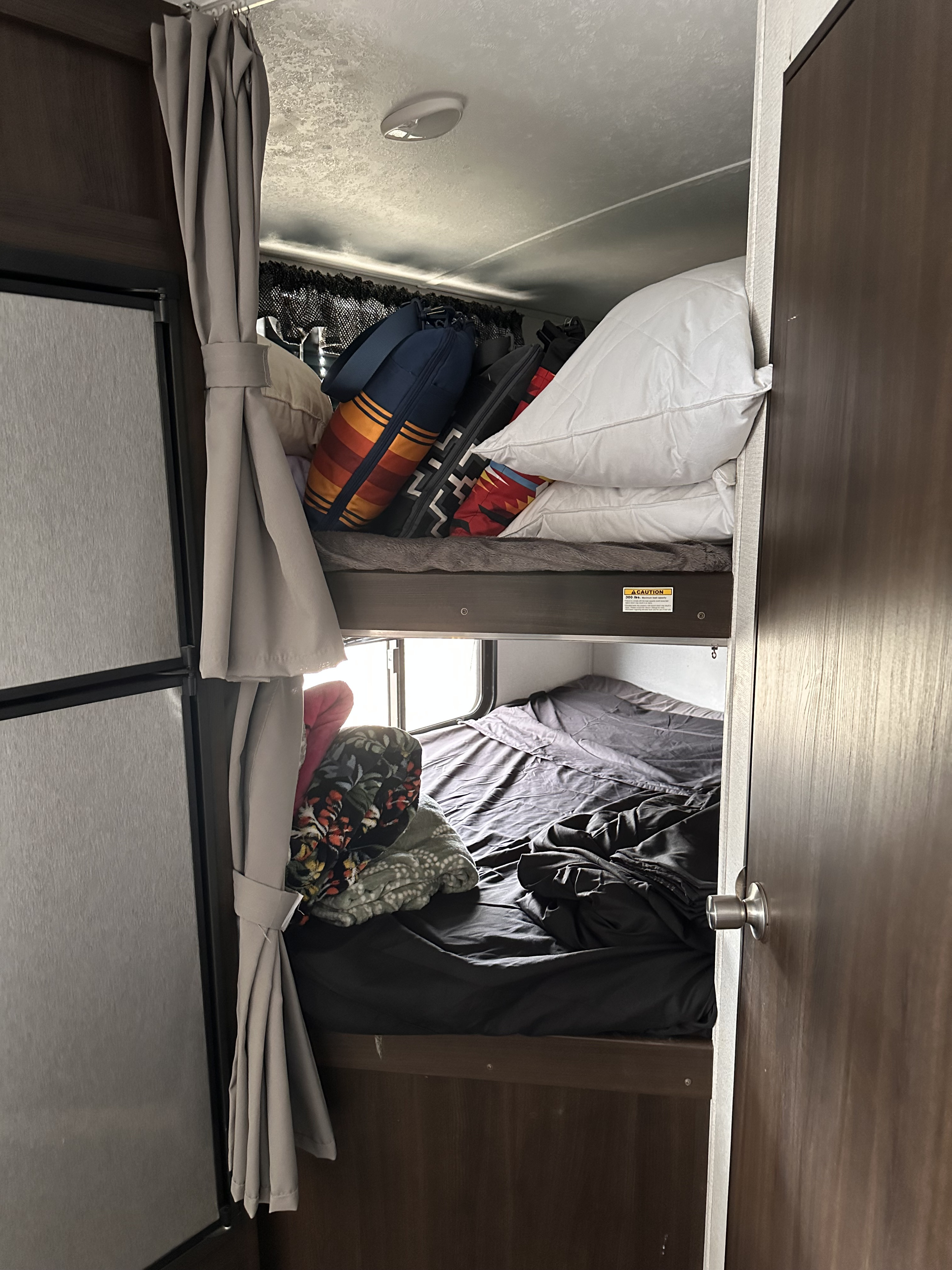 RV rental: Interior of a compact camper with stacked bunk beds and a refrigerator visible on the left.. Keystone RV Springdale 2020