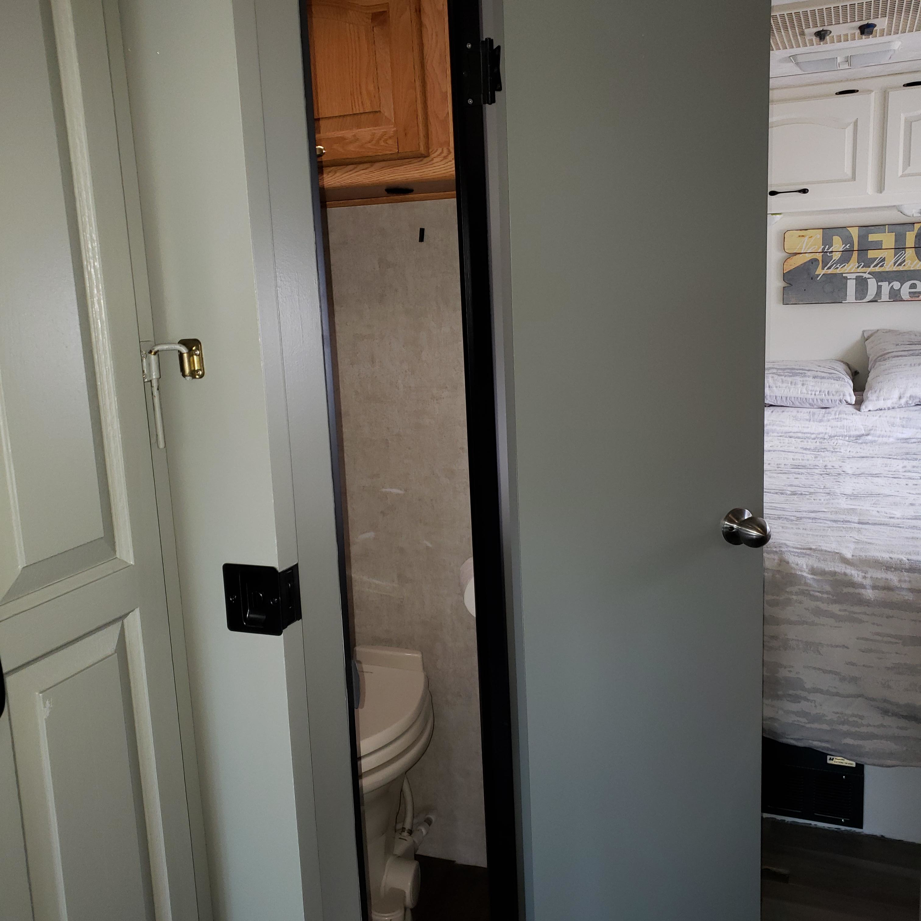 RV rental interior showing a compact bathroom with toilet visible through the door, and an adjacent bedroom.. Damon Corporation Daybreak 2002