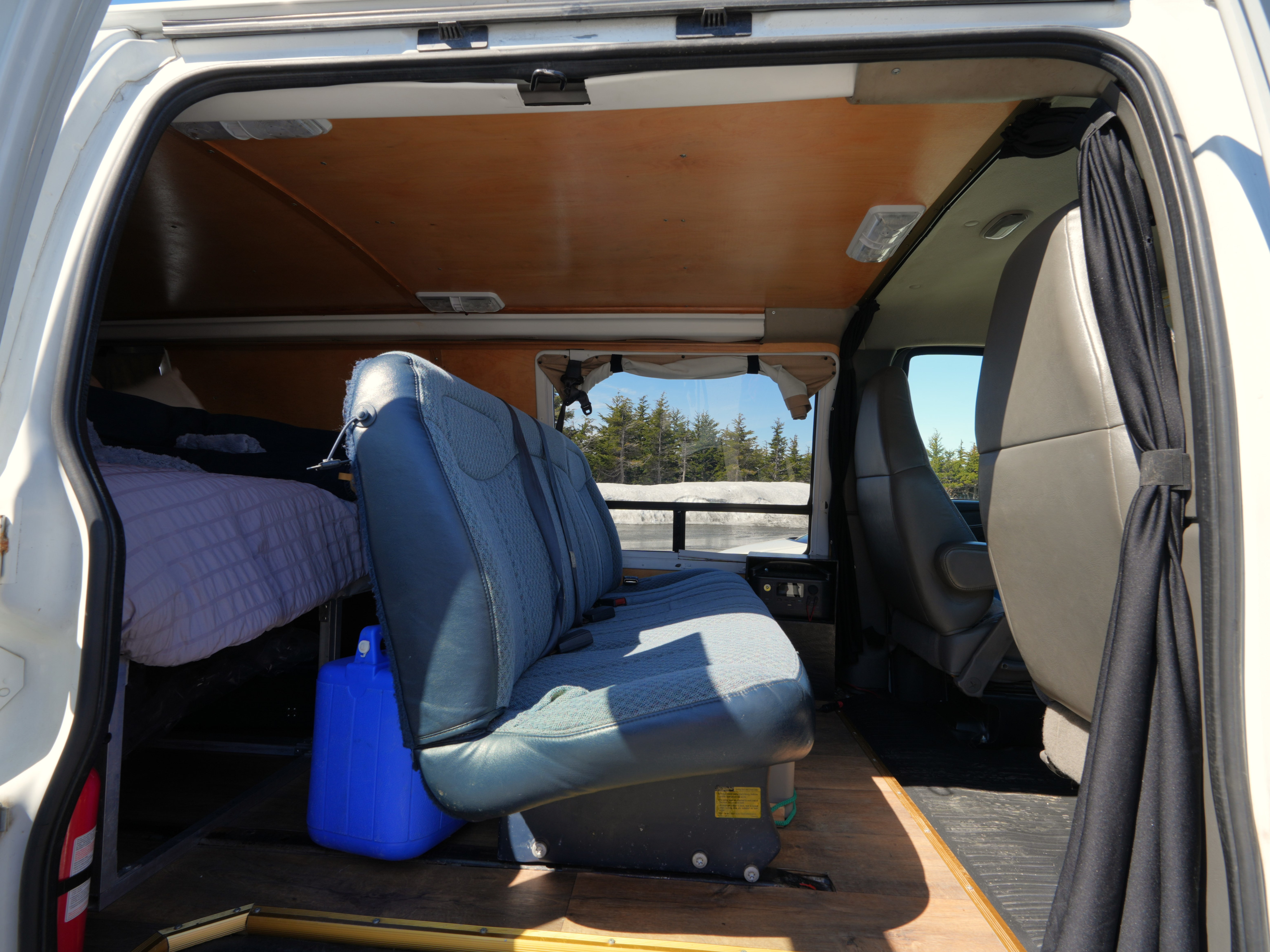 Inside a spacious RV rental camper van, featuring a comfortable bed, rear bench seat, and scenic winter window view.. Chevrolet Other 2006