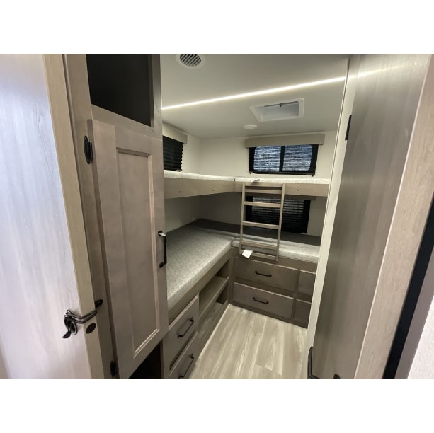 RV rental bunkhouse features: two beds with a ladder, built-in storage drawers, and light-toned interior finishes.. Grand Design Transcend Xplor 2024