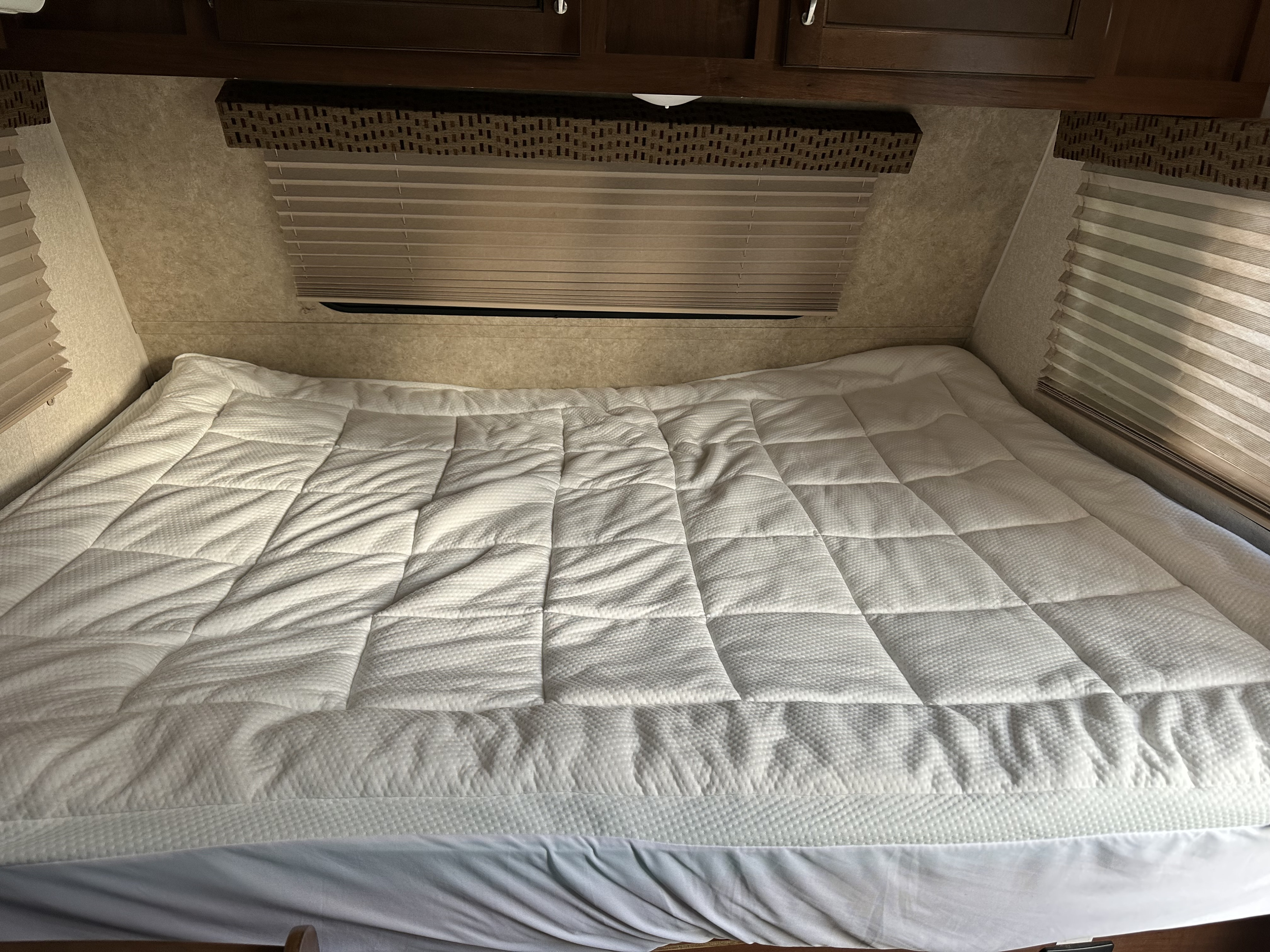 RV rental bedroom interior featuring a comfortable bed with a white quilted mattress topper and window blinds.. Jayco Jay Flight SLX 2017