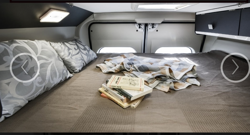Comfortable RV rental bed with plush pillows, a soft blanket, and reading books, ready for your next adventure.. McLouis MENFYS 3 MAXI 2024