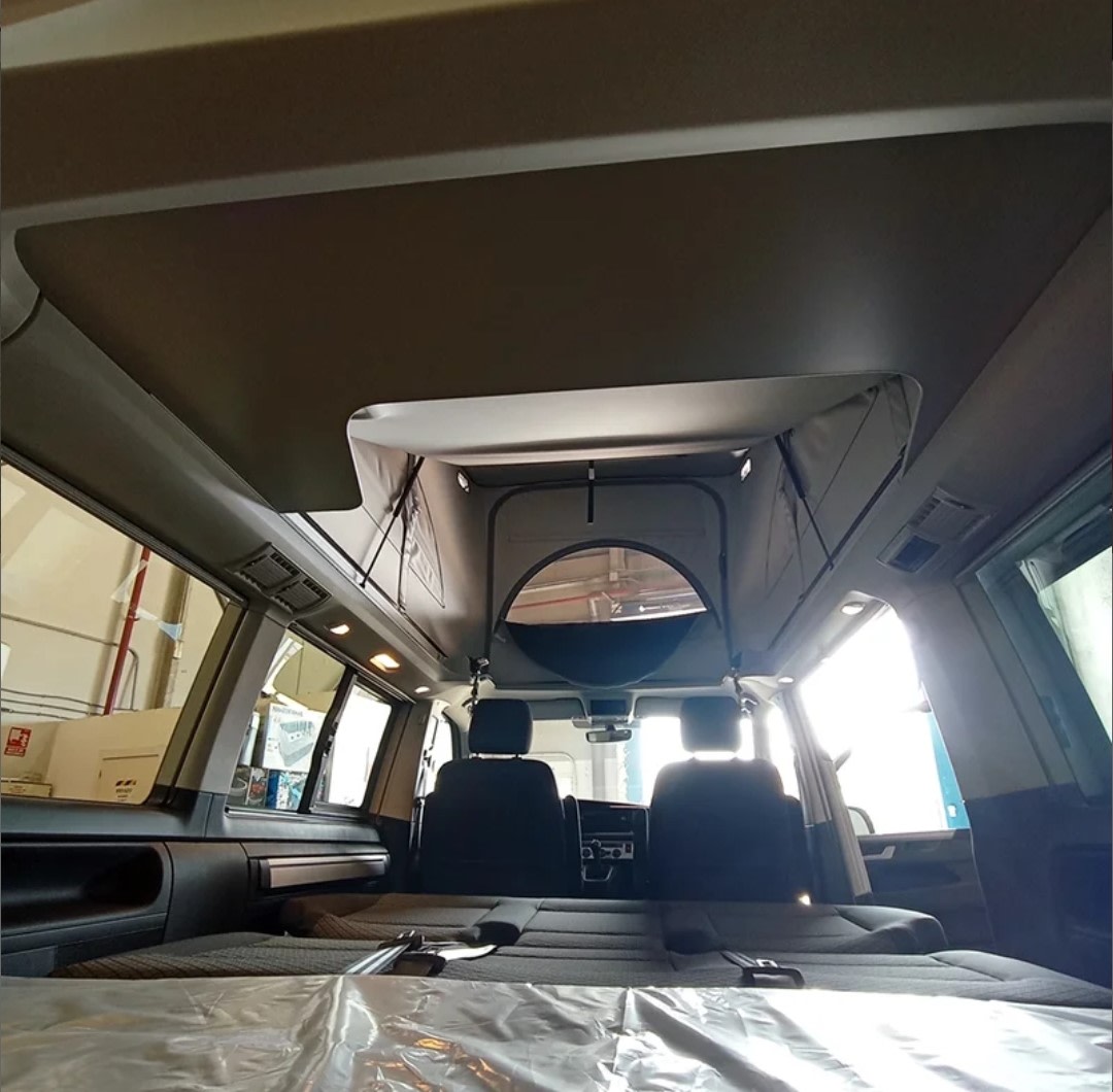 RV rental interior: A spacious camper van with a pop-top roof and bed, seen from the rear.. Volkswagen California Beach Camper 2.0 TDI 2023