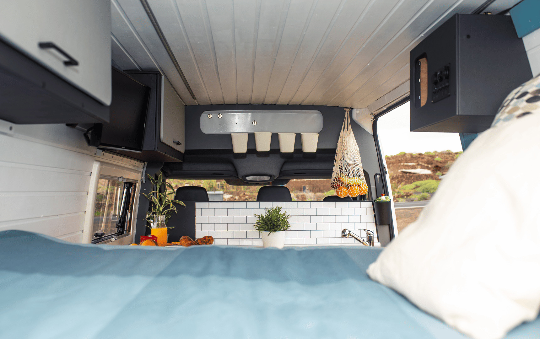 This RV rental's interior boasts a cozy bed, well-equipped kitchen, and TV, ideal for road trip comfort.. Mercedes Sprinter 2009