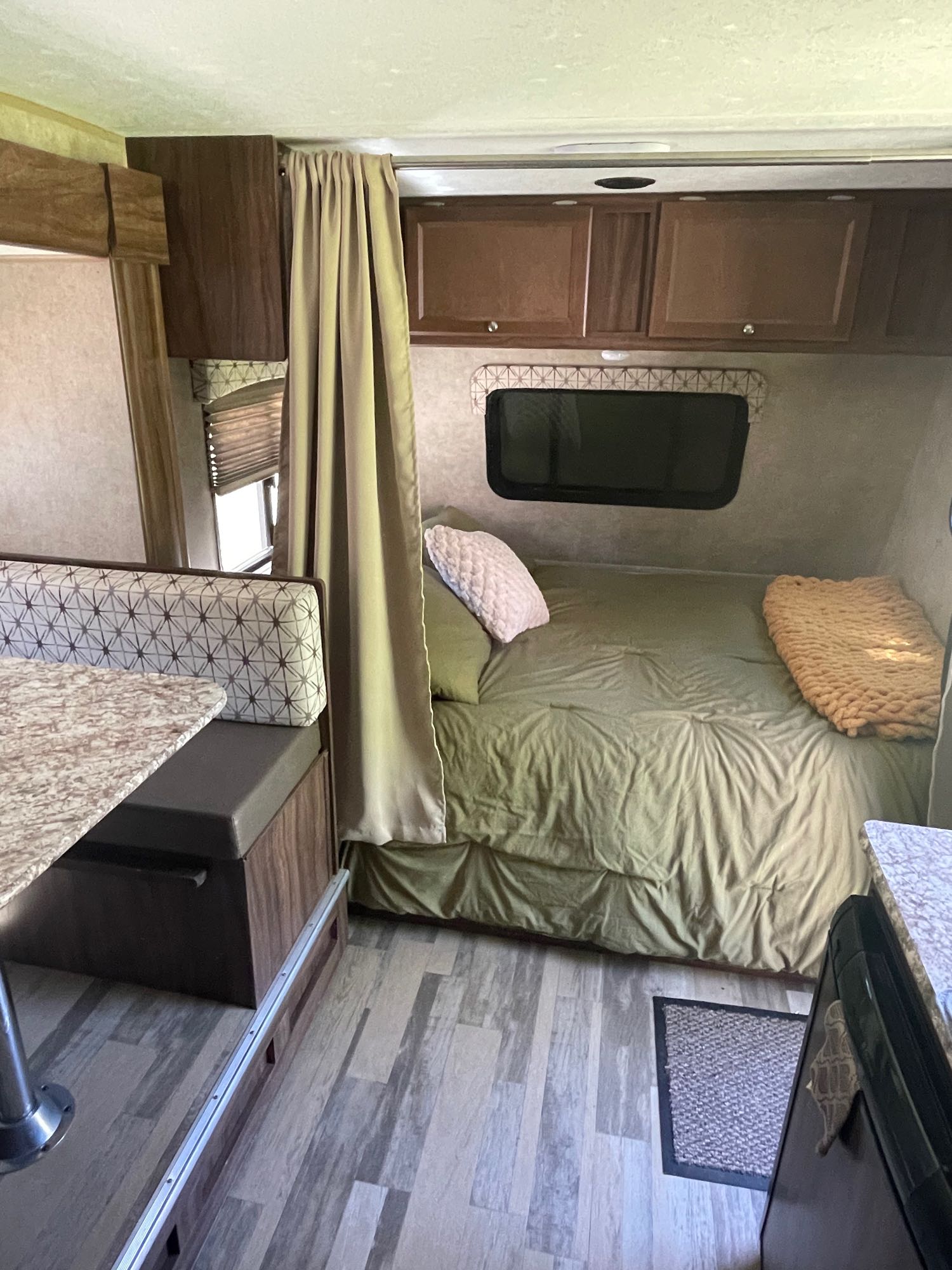 Experience comfort in this RV rental interior featuring a cozy bed, dinette with patterned seats, and wood cabinets.. Forest River Viking 2018