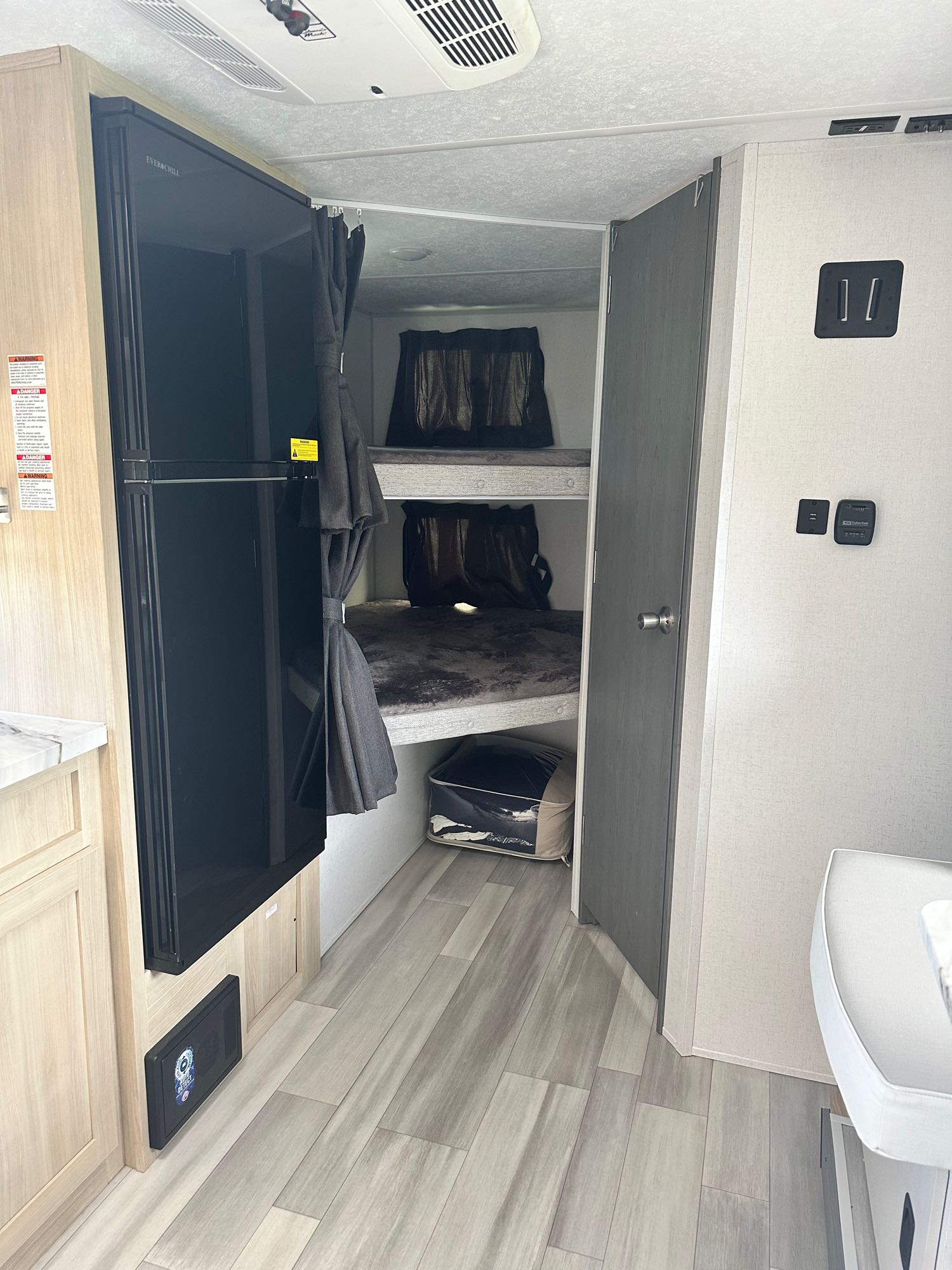 RV rental interior showcasing bunk beds with privacy curtains, a large fridge, and a functional living area.. Forest River Salem FSX Platinum 2023