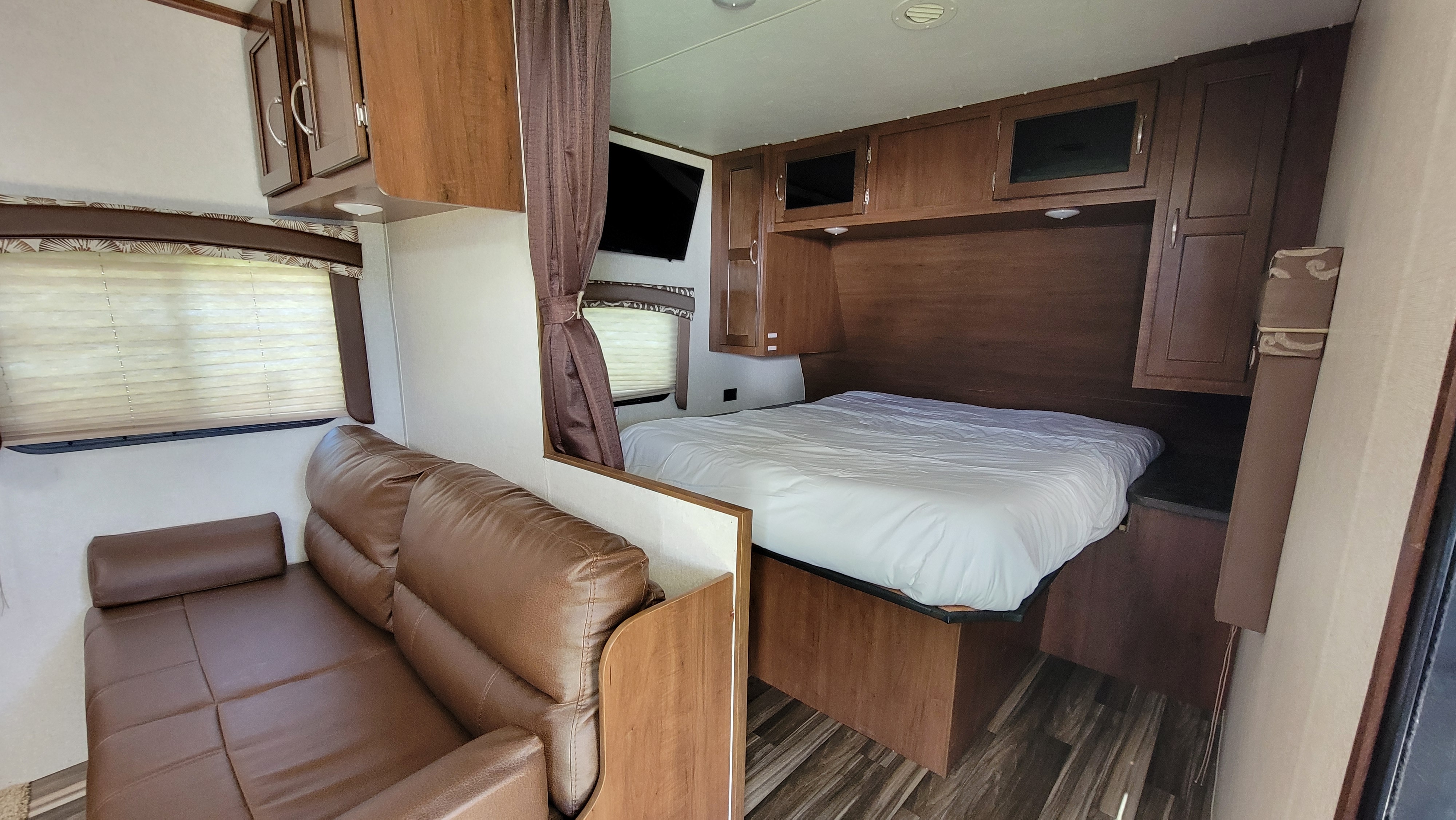 RV rental interior featuring a cozy living space with sofa, and a bedroom area with bed, TV, and storage.. jayco Jayflight 2017