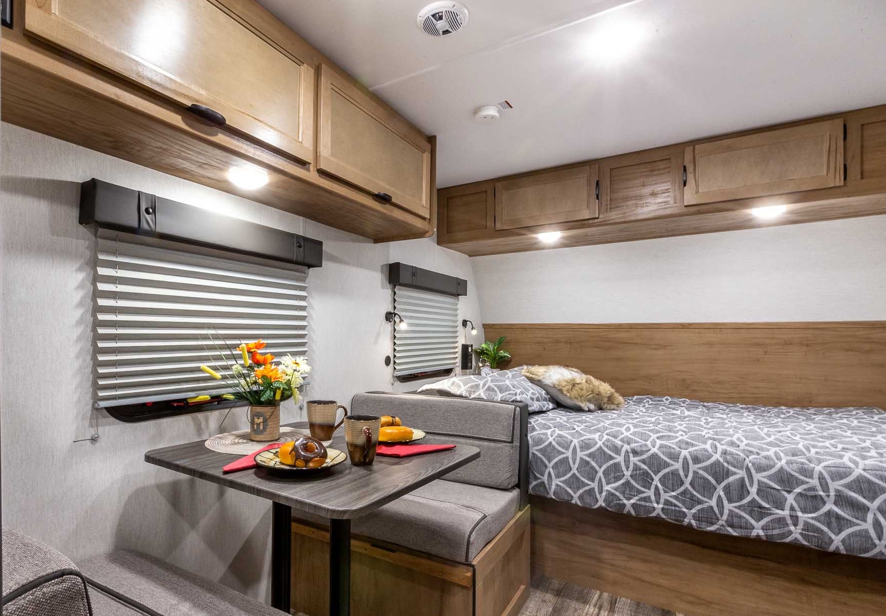 Inside an RV rental: a compact living space with a dining area, window blinds, comfy bed, and overhead storage.. Forest River Cherokee Wolf Pup 2024