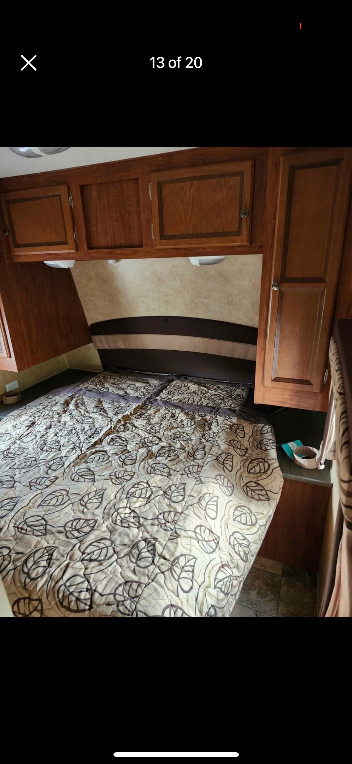 Inside an RV rental: a comfortable bedroom with a leaf-patterned bed, headboard, and wood cabinets. Ideal for travel.. Jayco Jay Flight 2012