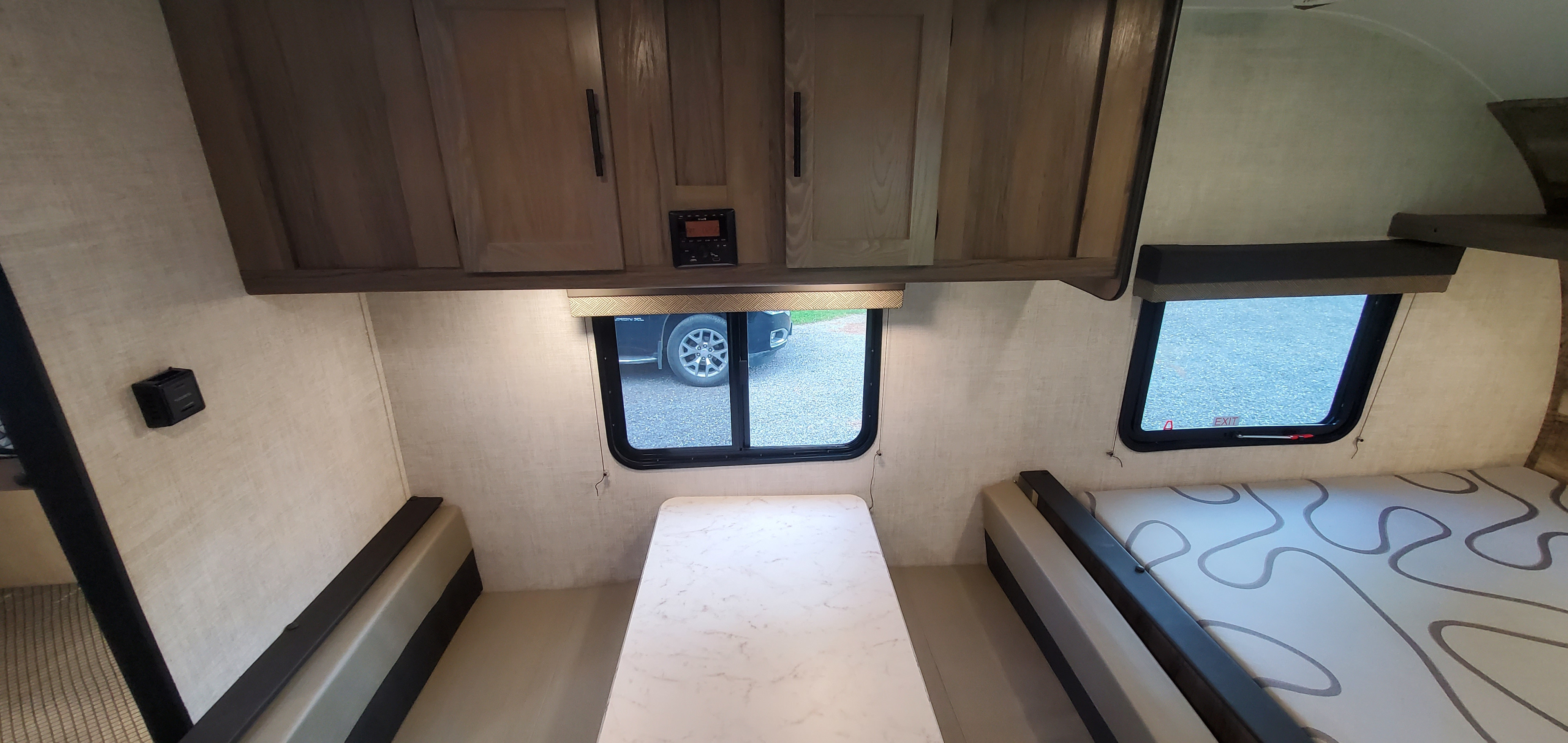 RV rental interior with a dinette, central table, overhead cabinets, and a patterned bed.. Gulf Stream Trailmaster 2022